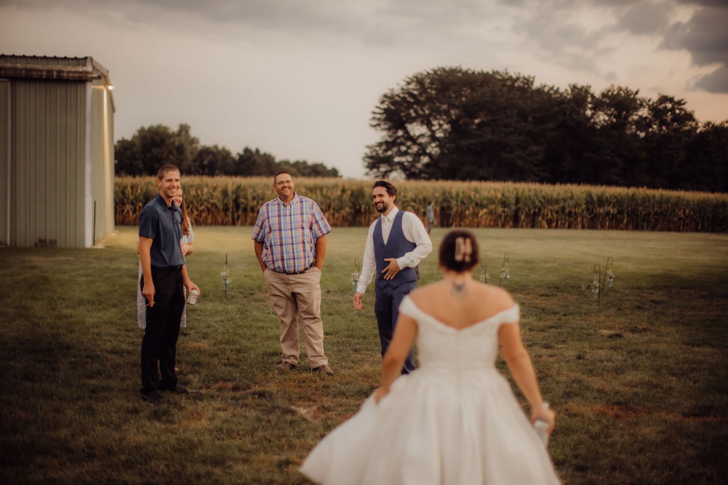 Evening wedding photos taken outside a rustic barn with cornfields in the background.