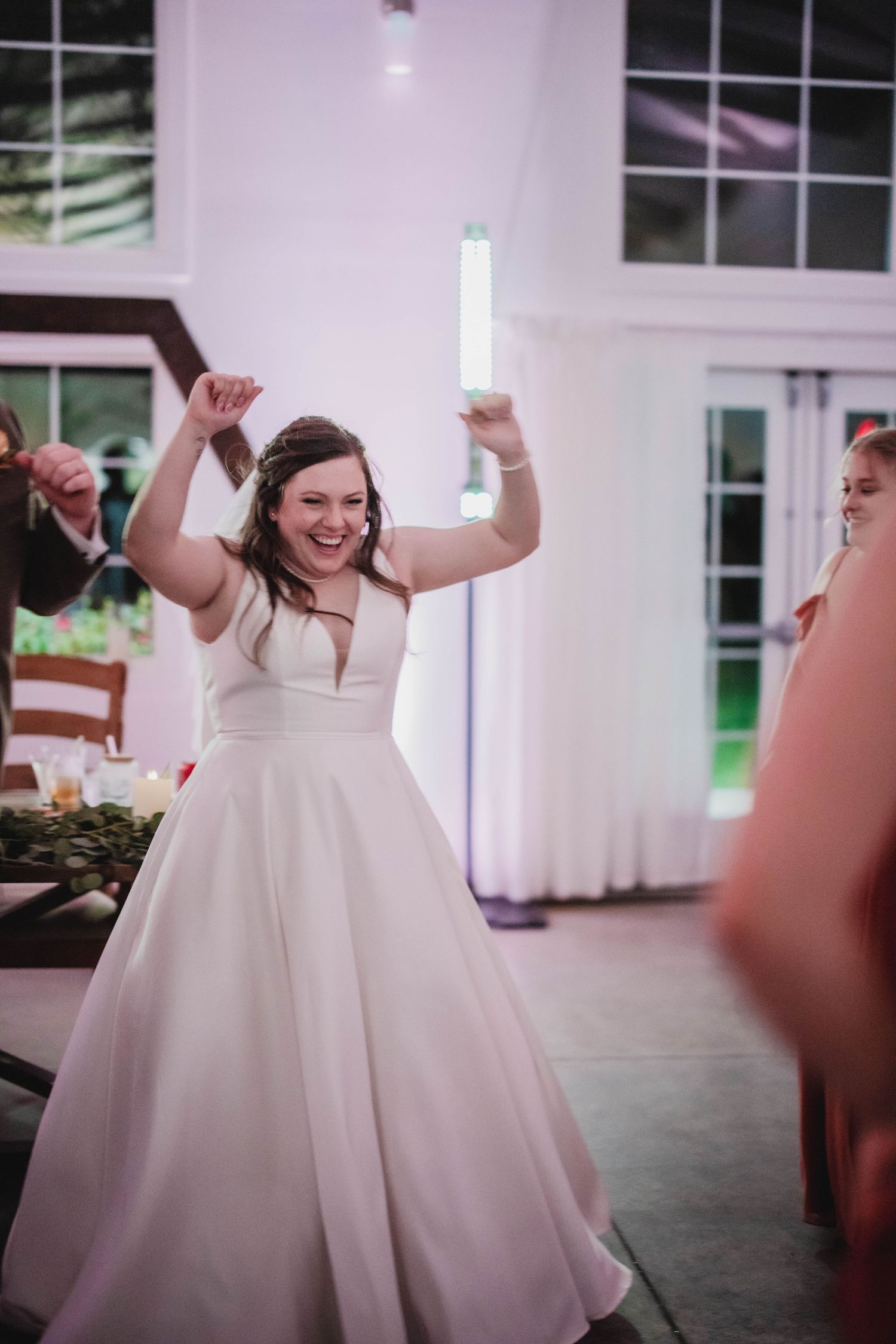 A bride in a flowing white ball gown dances exuberantly at her wedding reception.
