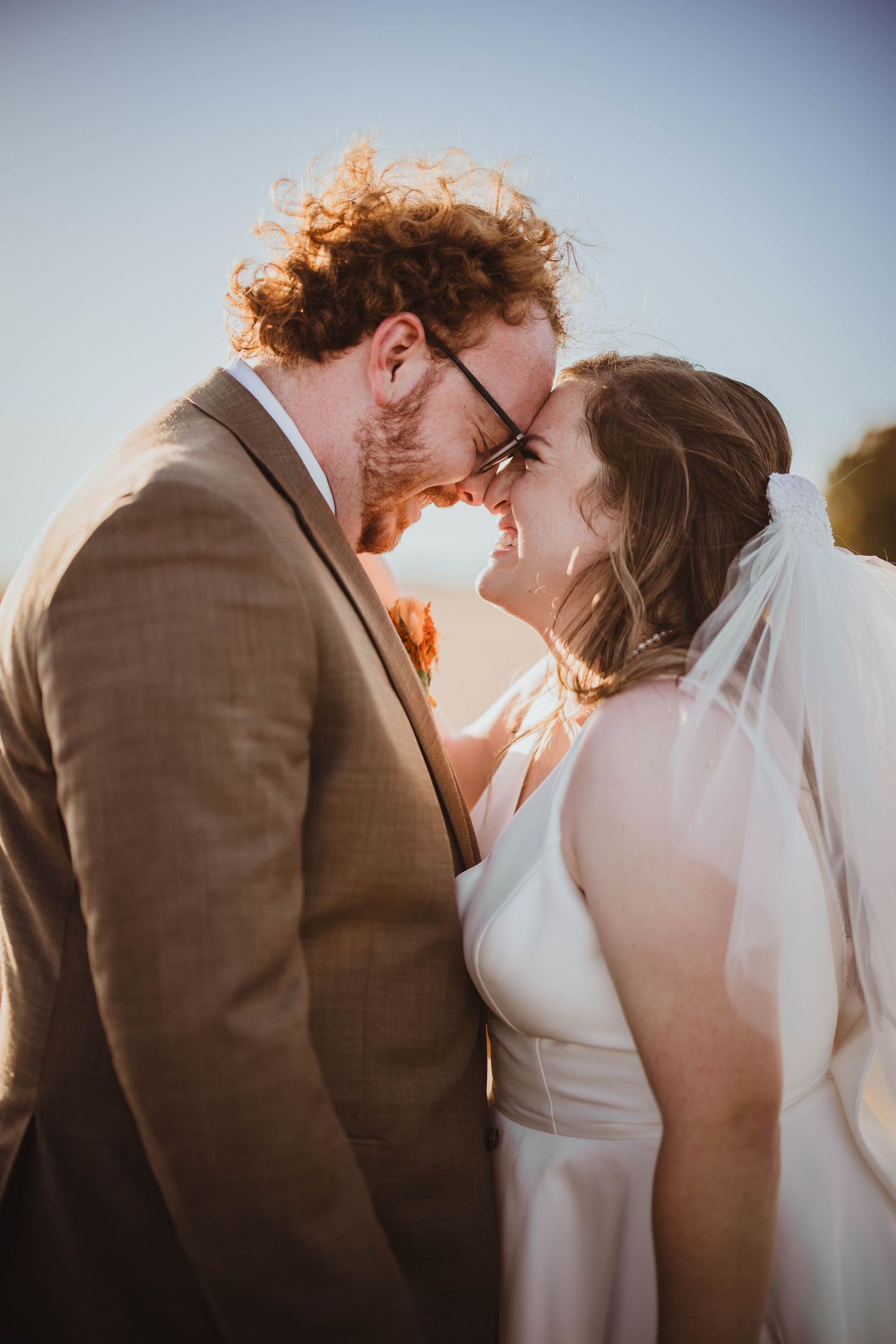 Wedding couple sharing romantic moments together in a field during golden hour.