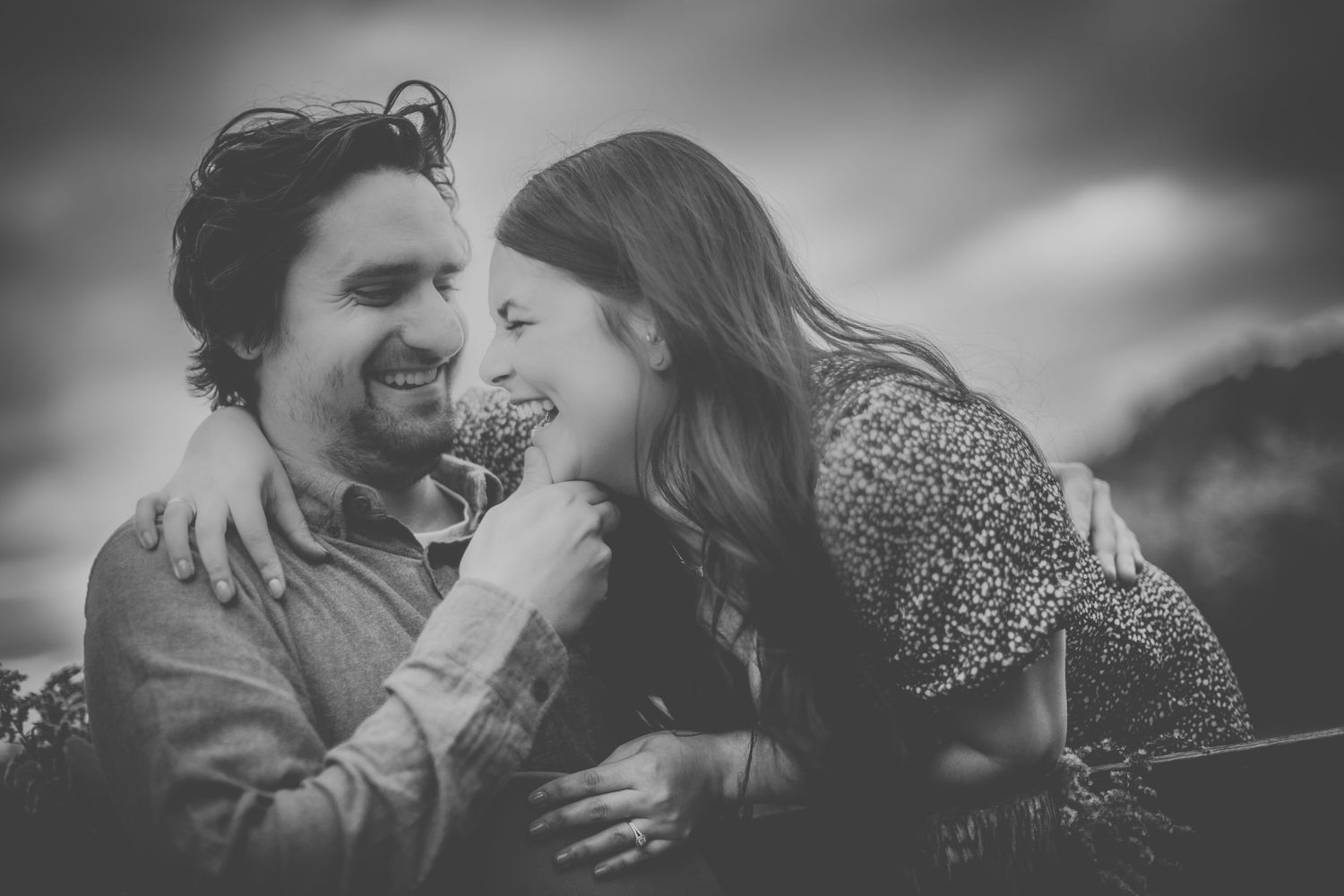 Black and white capture of couple sharing authentic laughter during intimate moment.