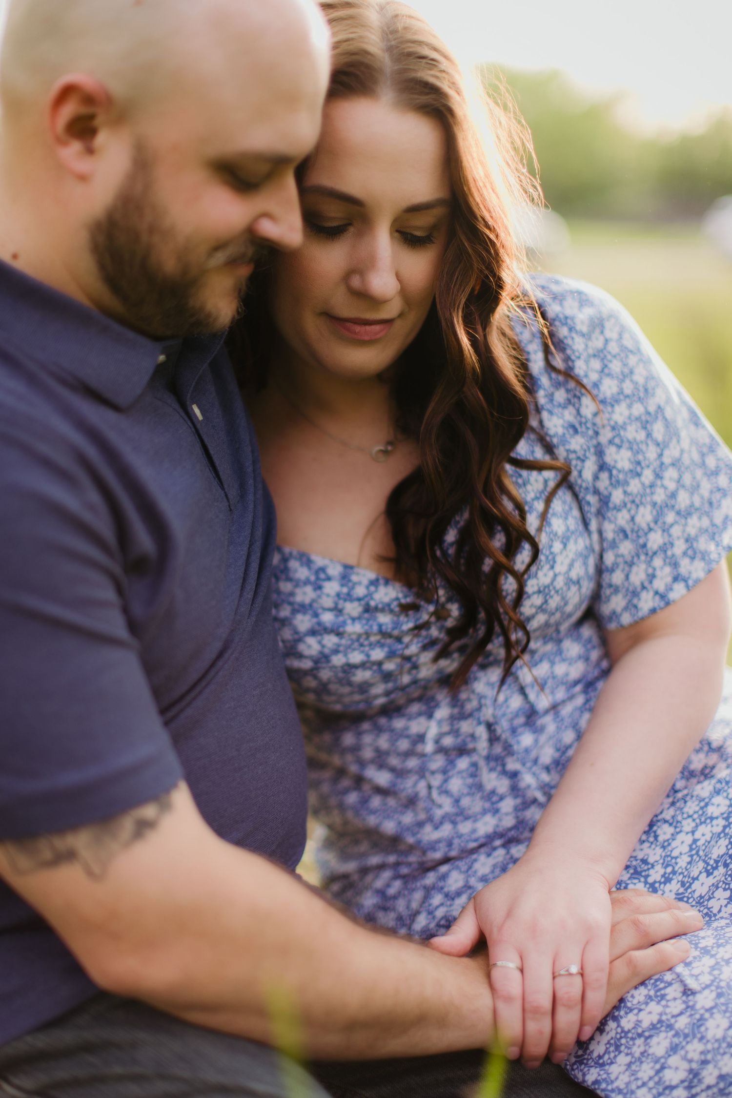 A close-up portrait showing hands clasped together during an outdoor couples photoshoot.