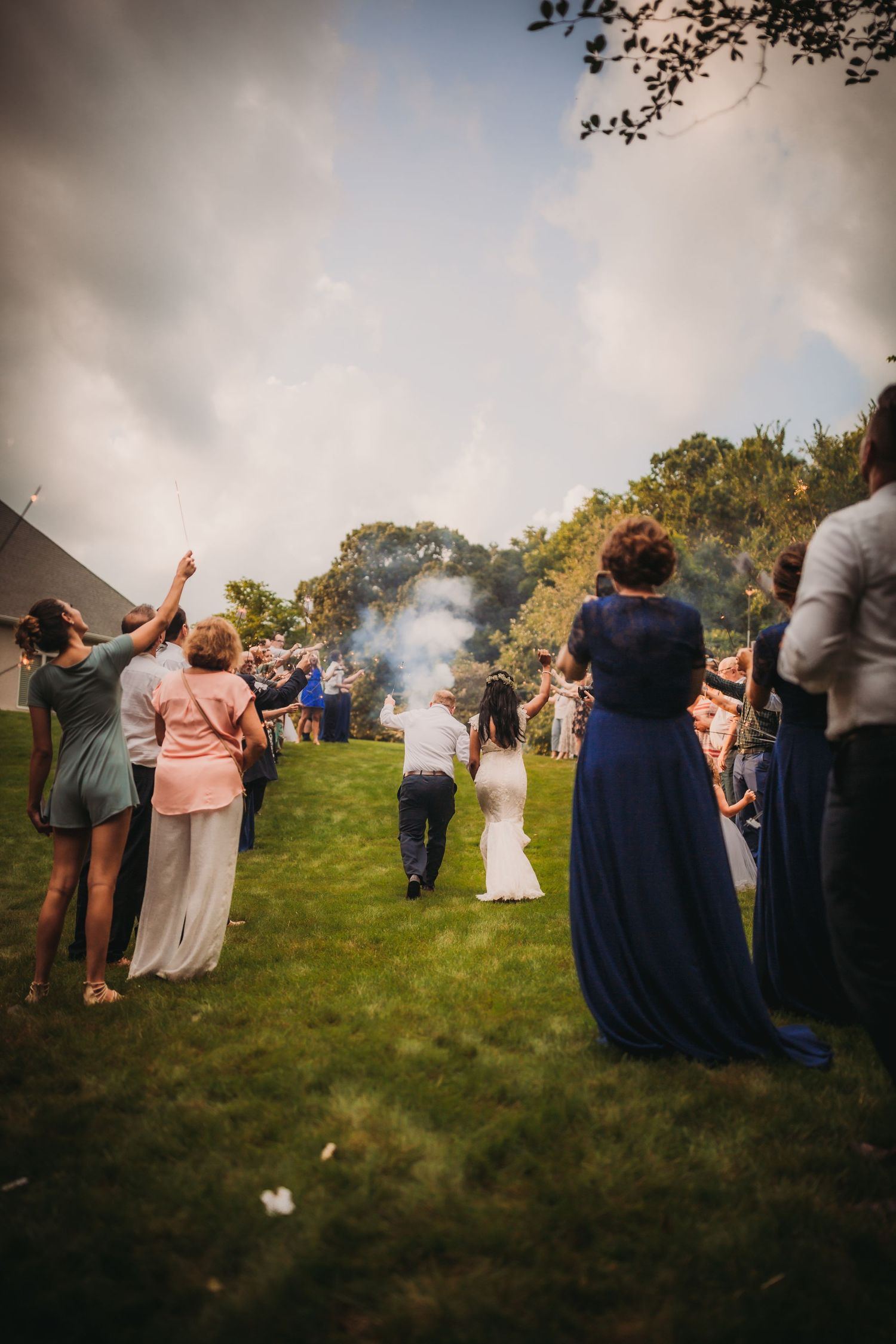 Wedding celebration with smoke effects and guests celebrating outdoors.