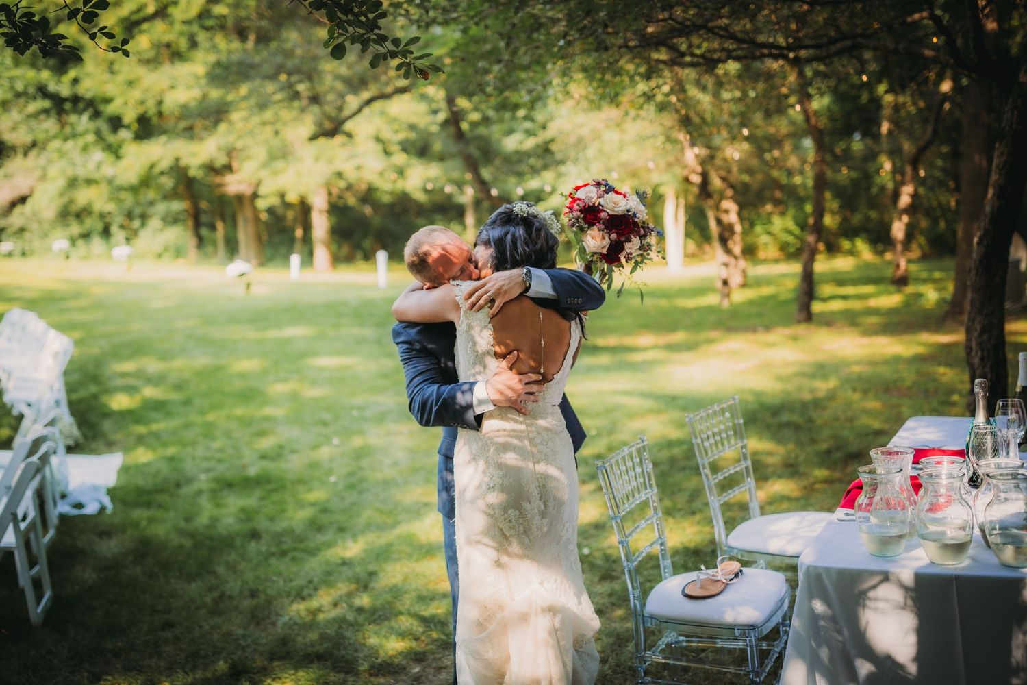 Wedding reception tables decorated with flowers and place settings in an outdoor forest setting.