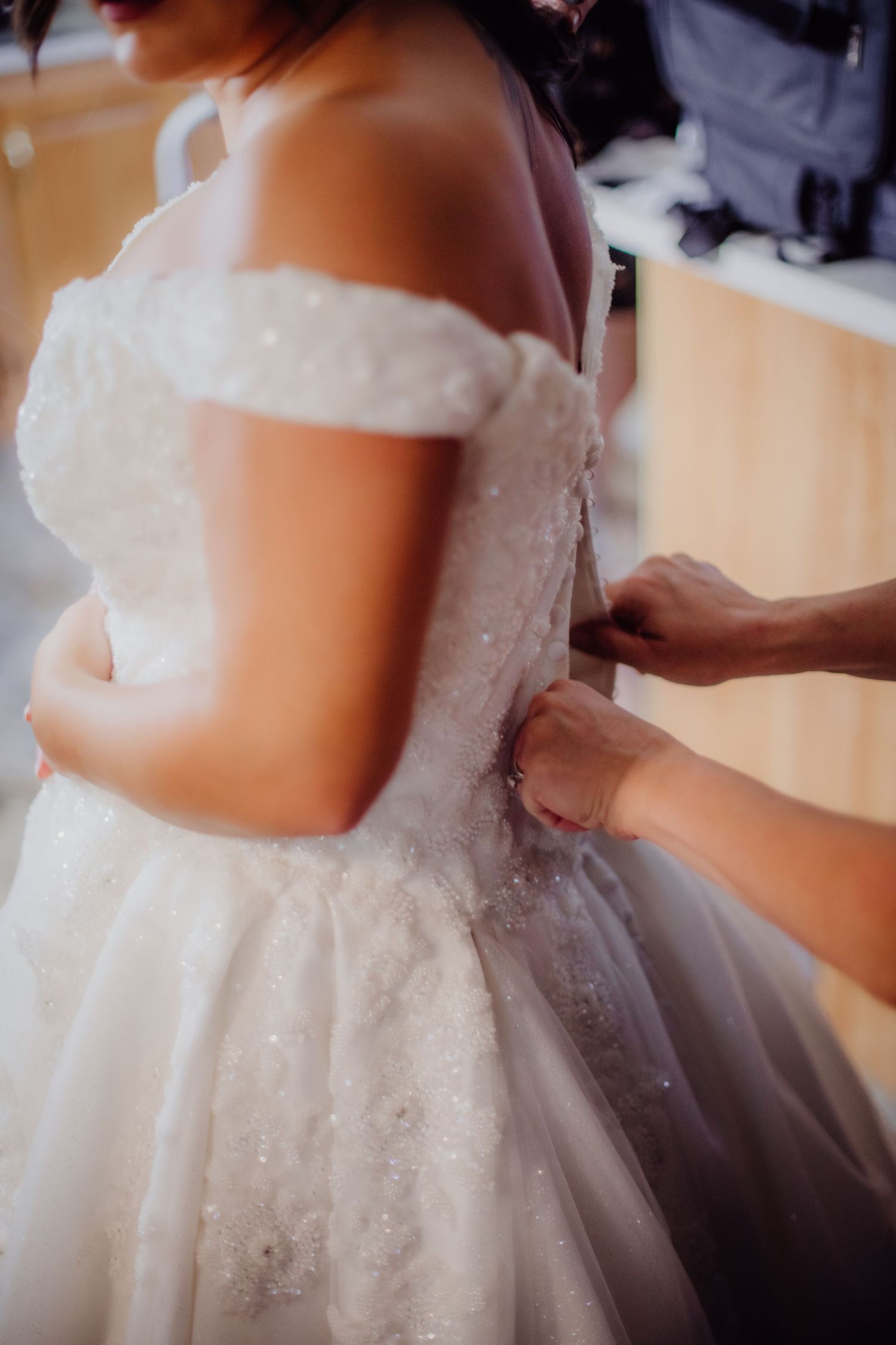 Detailed view of a white lace wedding gown with off-shoulder design.