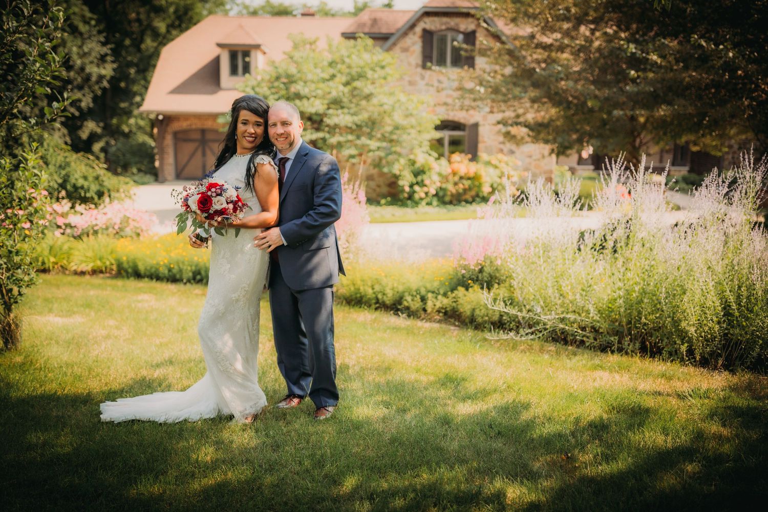 Wedding couple poses together on the grounds of an elegant estate.