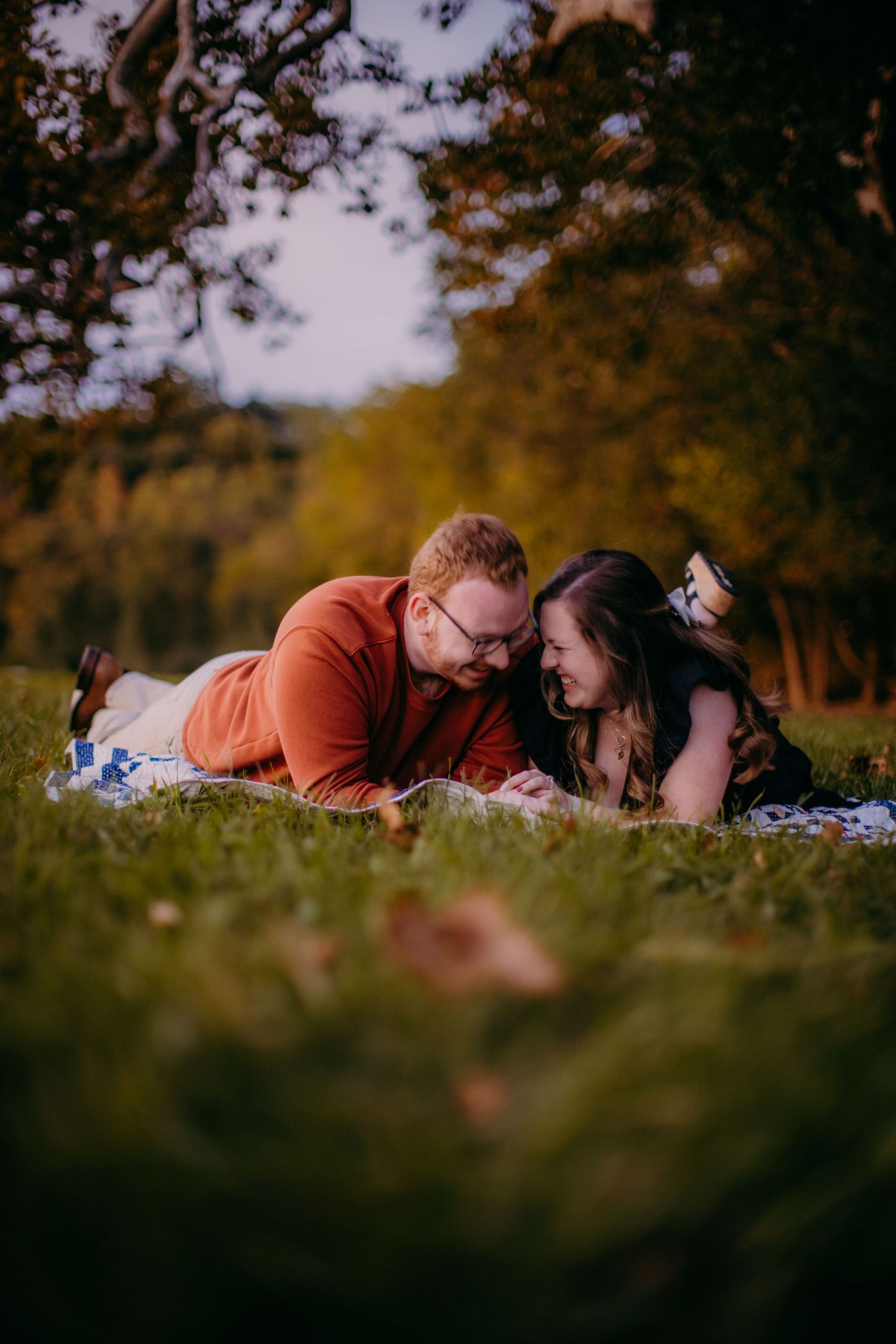 Couple laughing together during romantic outdoor photo session in autumn setting.