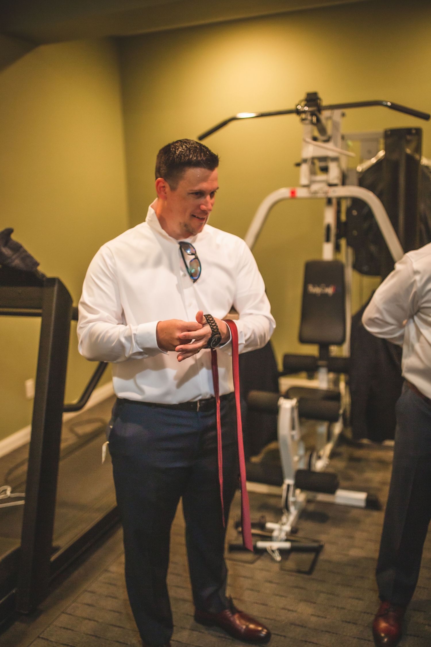 Person in white dress shirt and tie standing near exercise equipment.