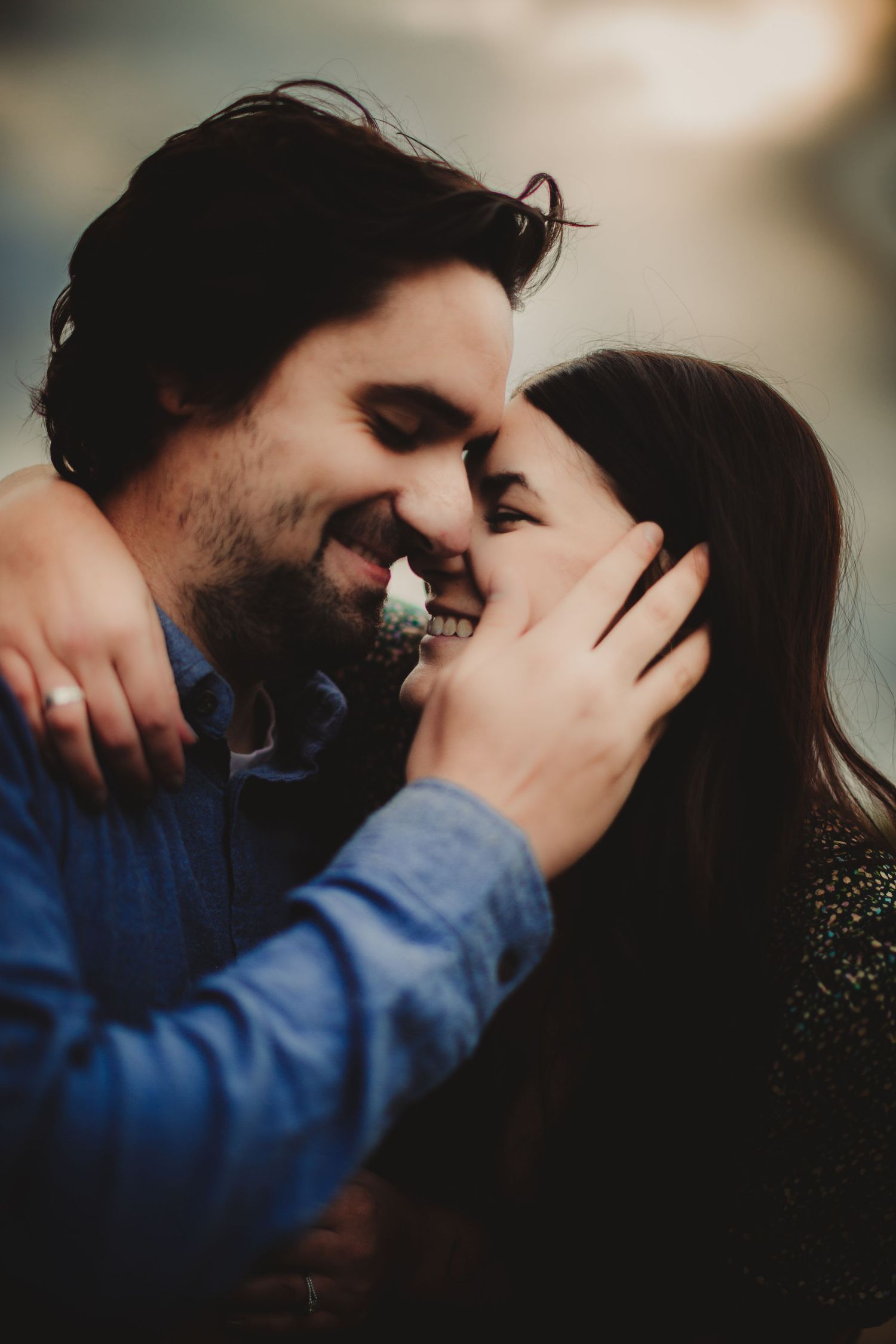 Romantic couple sharing an intimate moment outdoors with joyful laughter and gentle embrace.
