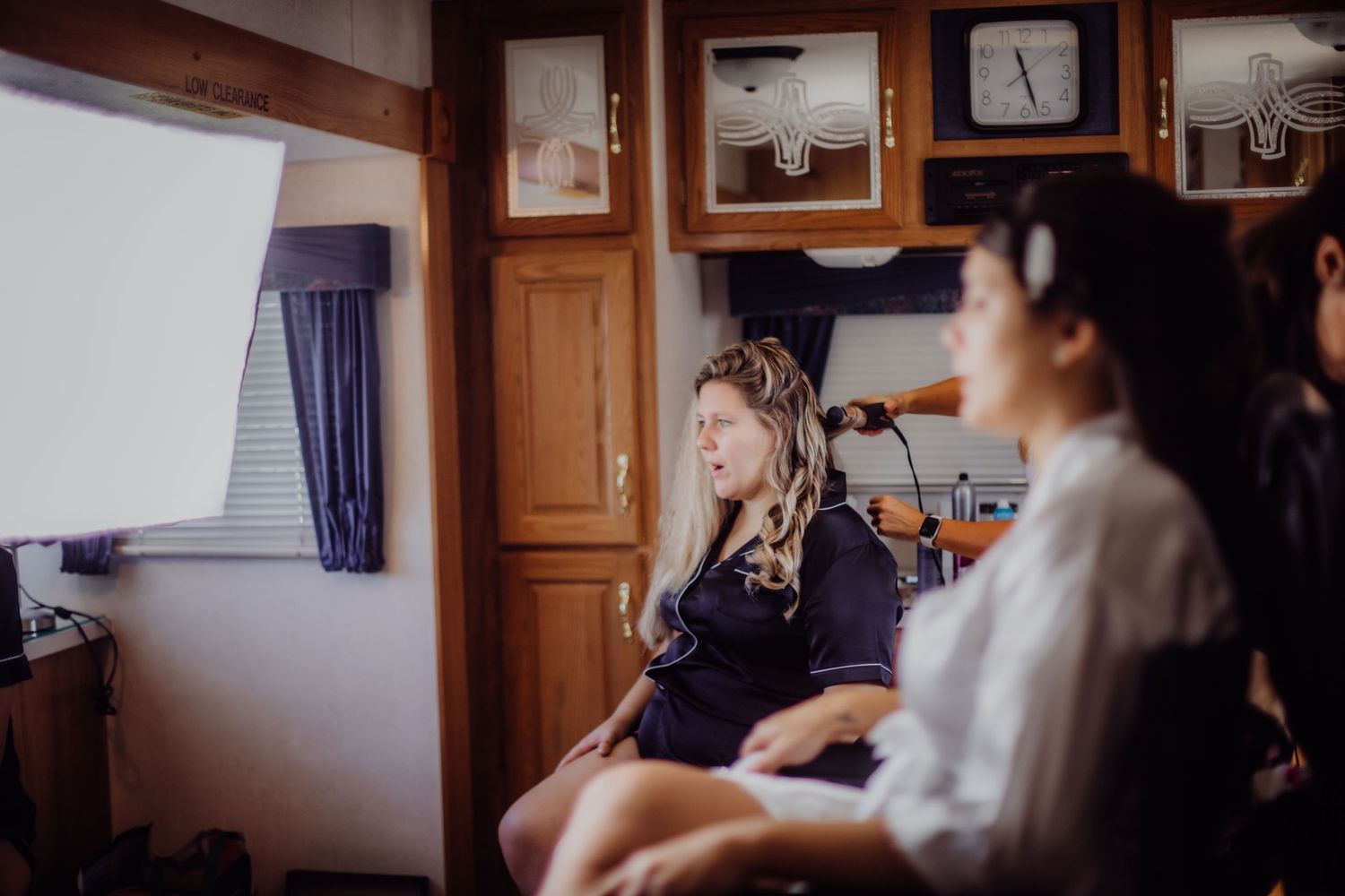 Wedding preparation scene in a wood-paneled room with framed photos on the wall.