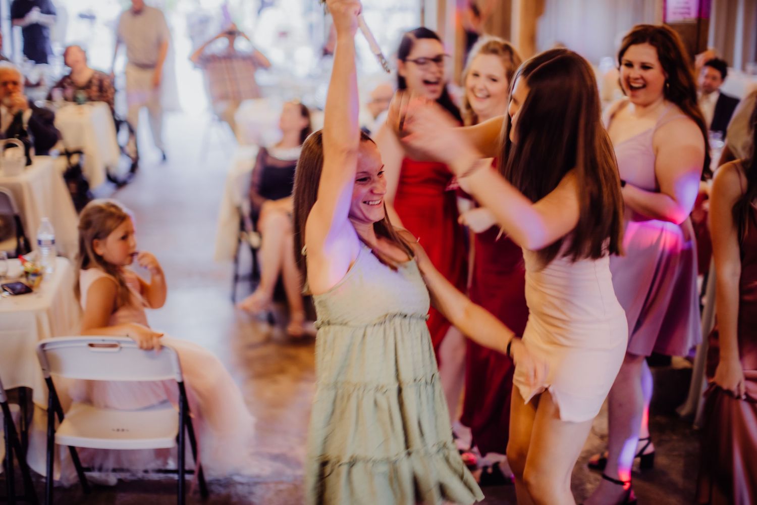 Wedding party dancing and celebrating on the dance floor with colorful mood lighting.