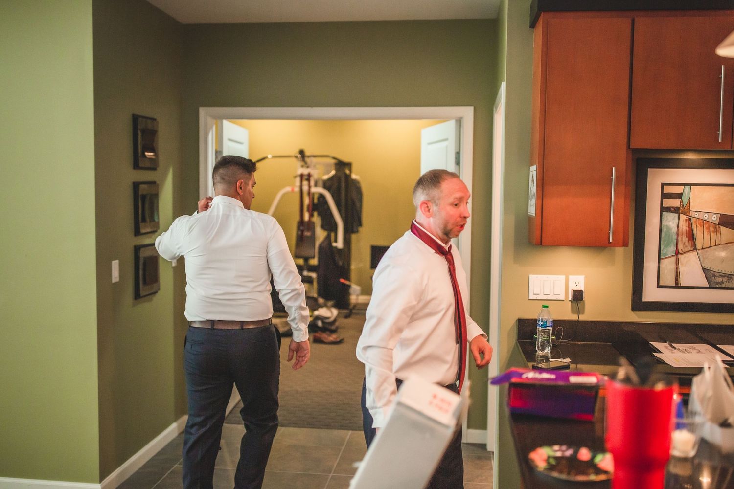 Two people walking through hallway of venue with kitchen visible in background.