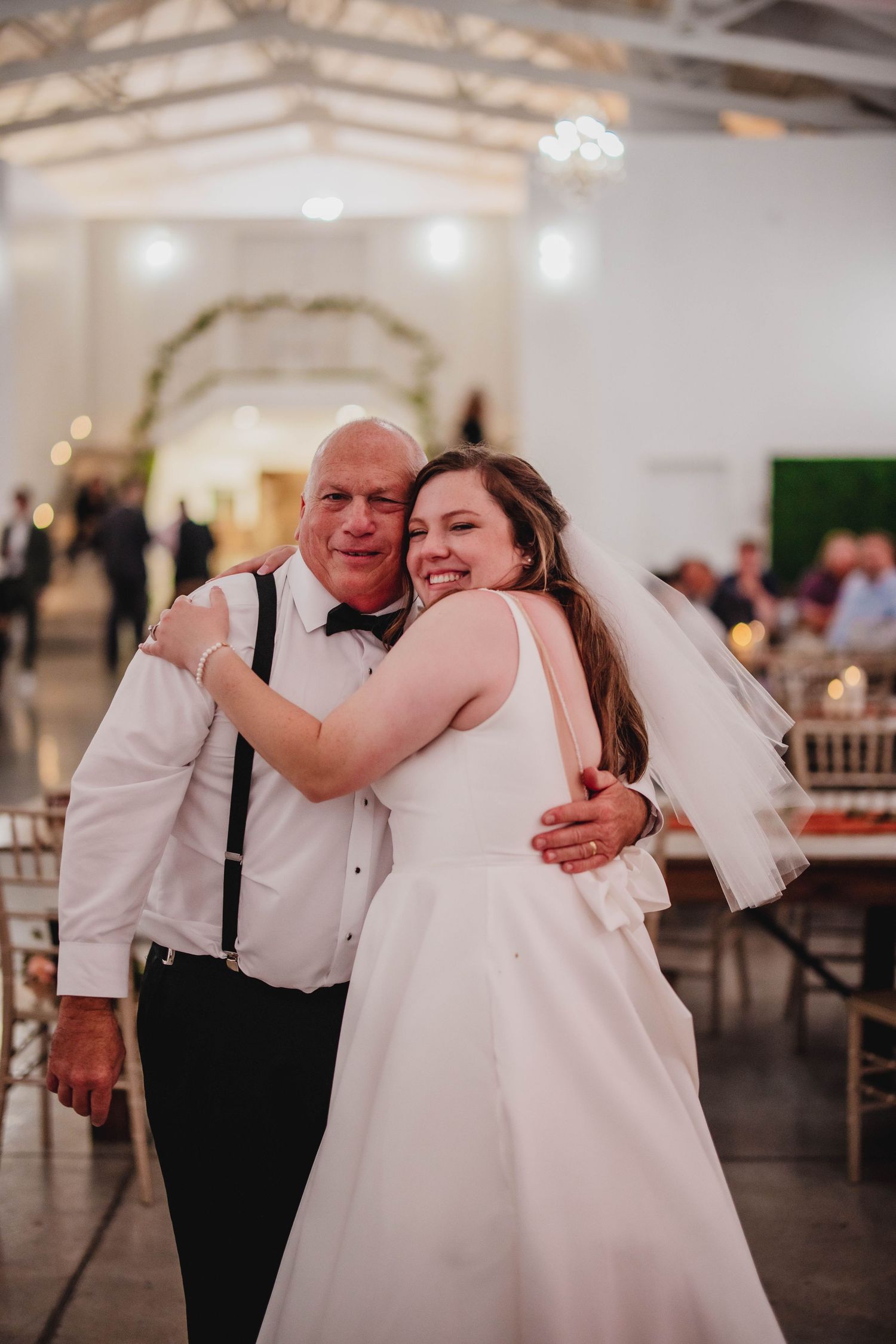 A joyful embrace shared between a bride and her dance partner at a wedding reception.