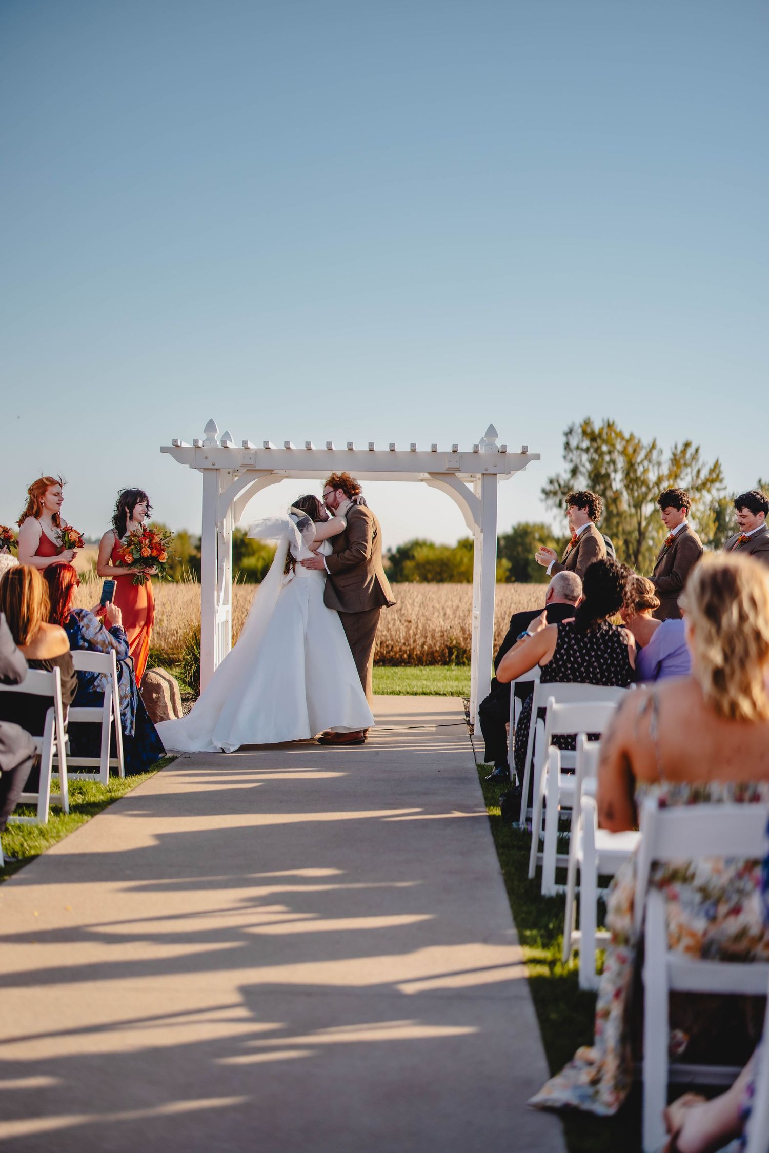 Romantic moment captured during sunset wedding ceremony under white pergola.