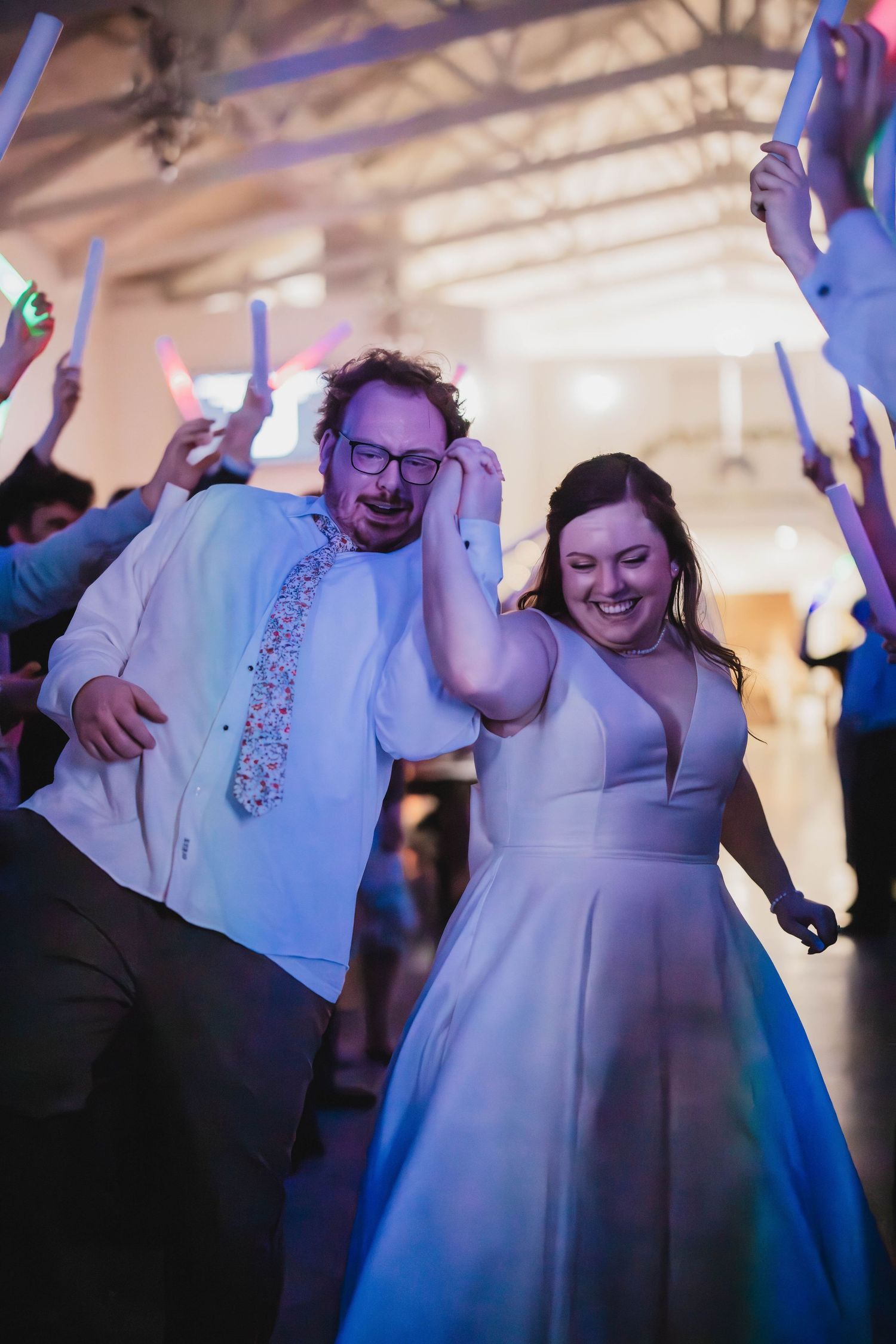 Newlyweds enjoying a lively dance moment surrounded by guests with illuminated wands.