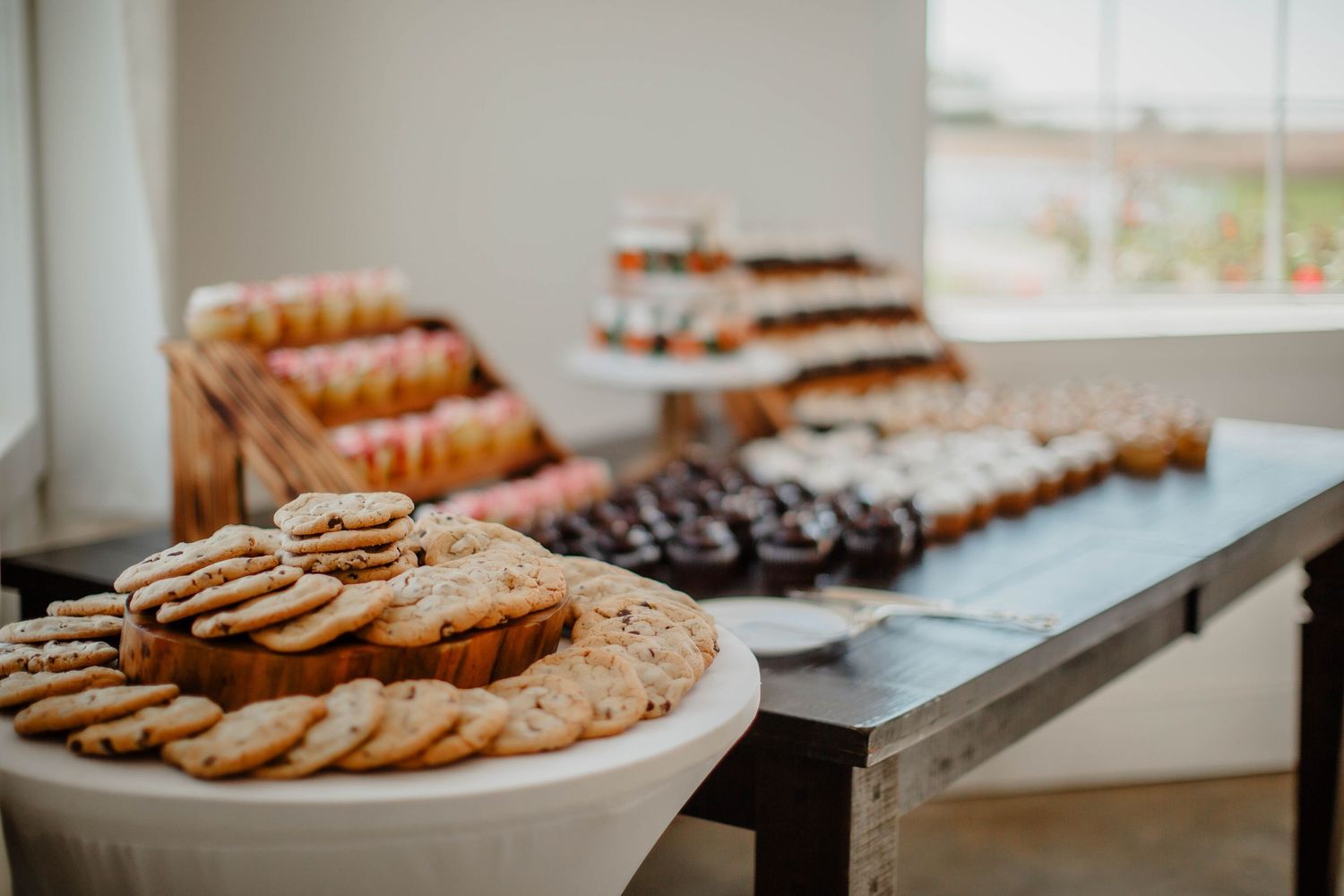 Assorted cookies and pastries arranged on white serving plates for an event.
