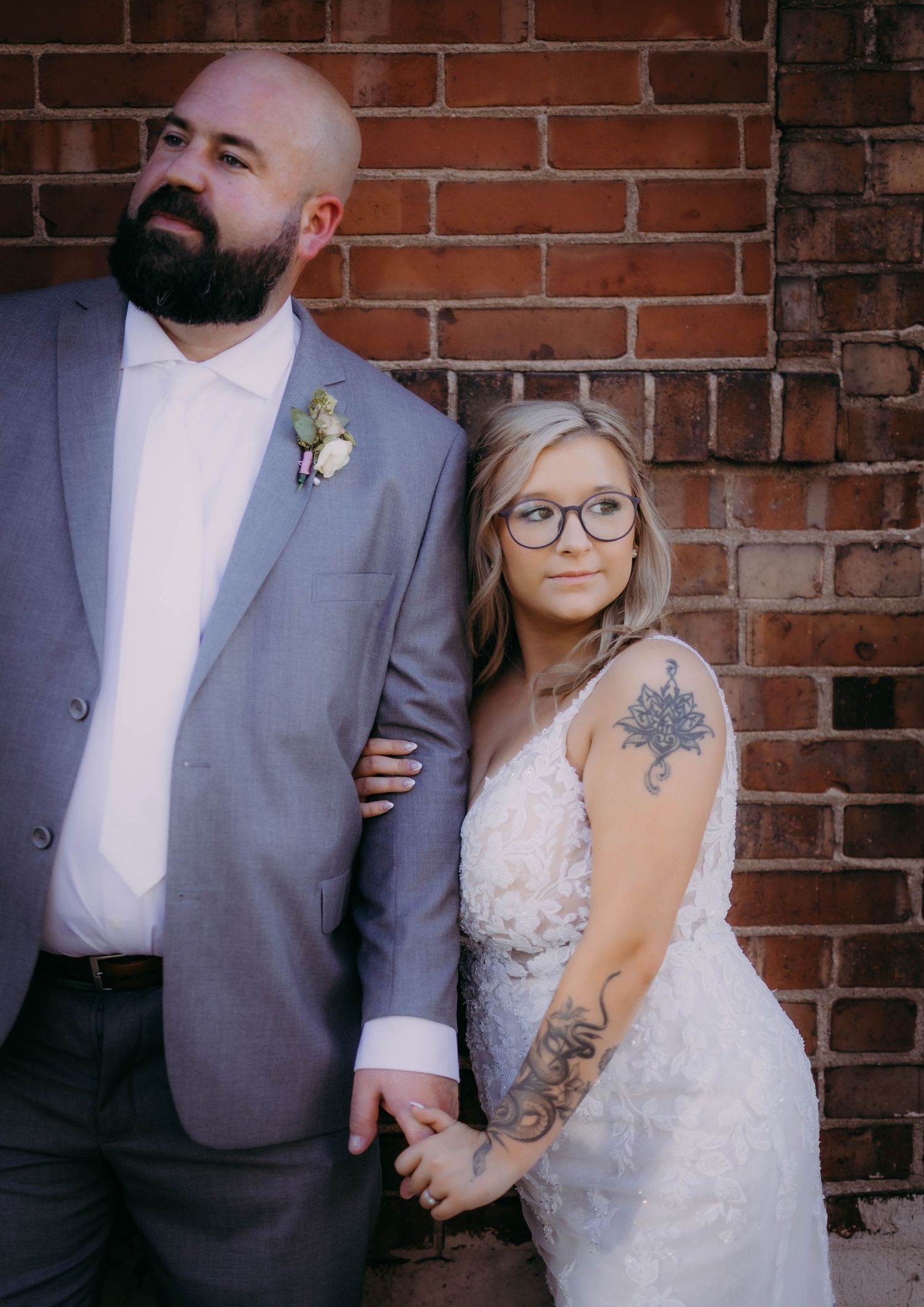 A classic wedding portrait against red brick showing the couple in formal attire.