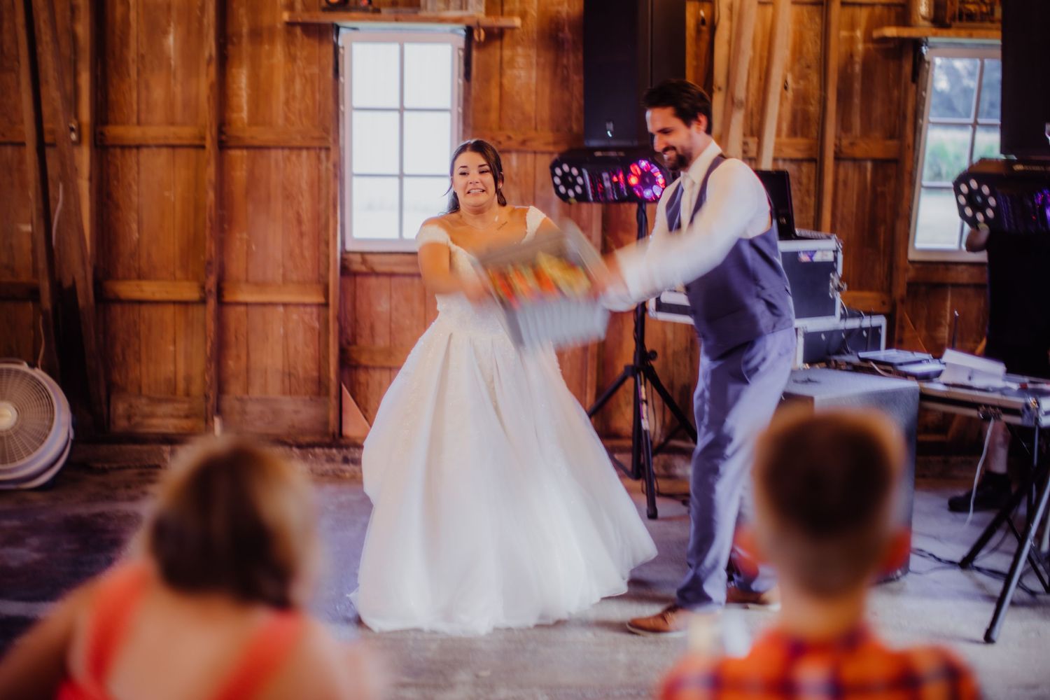Bride and groom performing a playful dance routine in a rustic wooden barn setting.