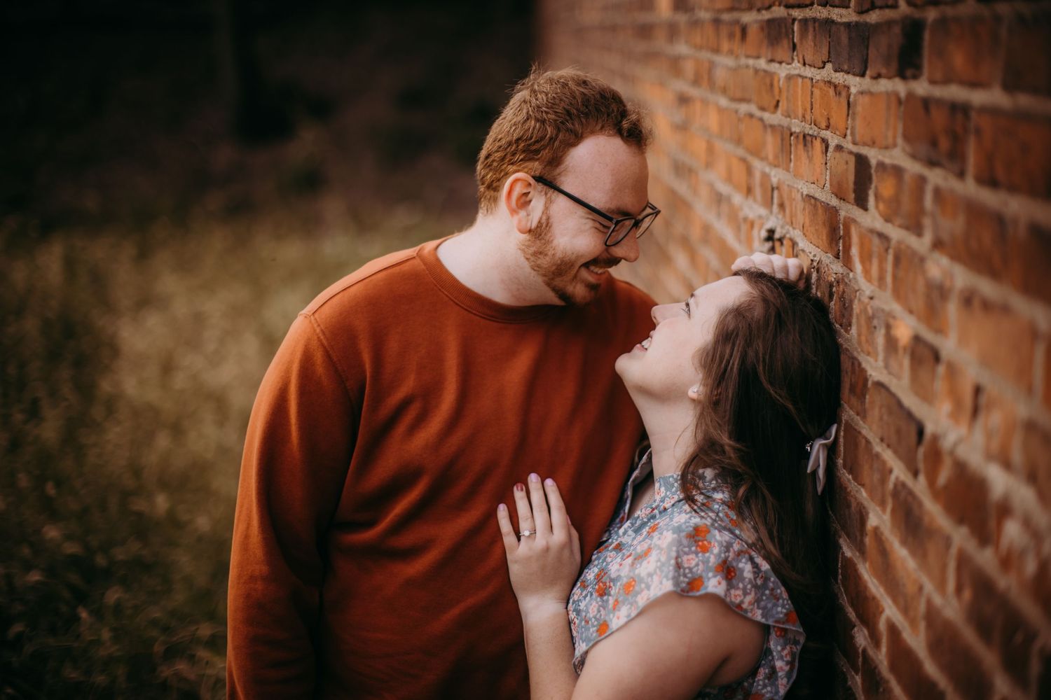 A romantic photoshoot captures sweet embraces and laughter against weathered brickwork.