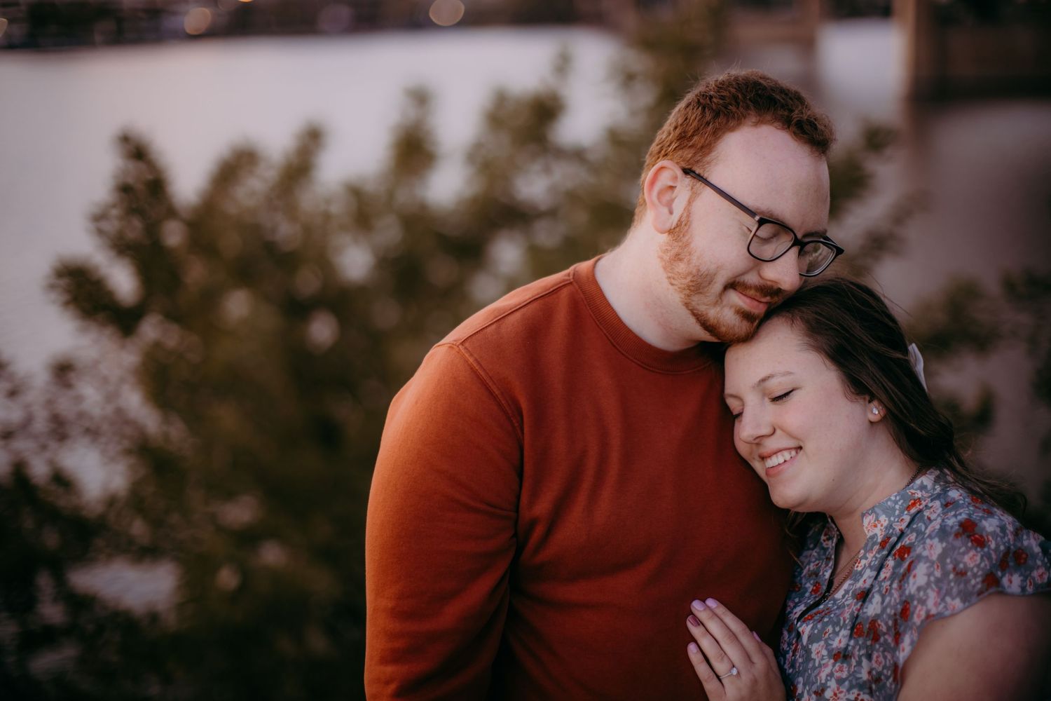 A romantic portrait of a couple laughing together during sunset by the water.