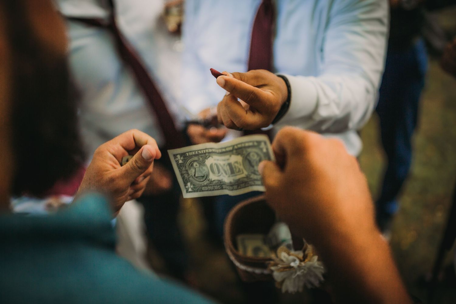 Close-up of hands exchanging money during outdoor celebration.