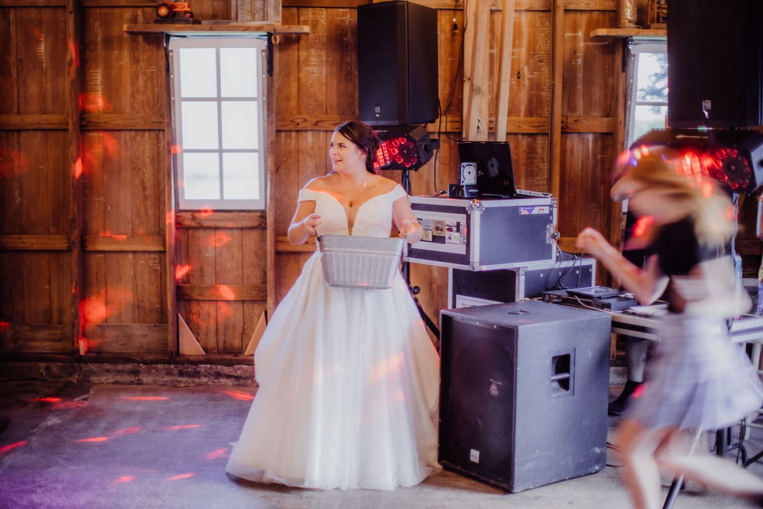 Couple dancing together in a rustic barn venue with warm lighting and wooden walls.