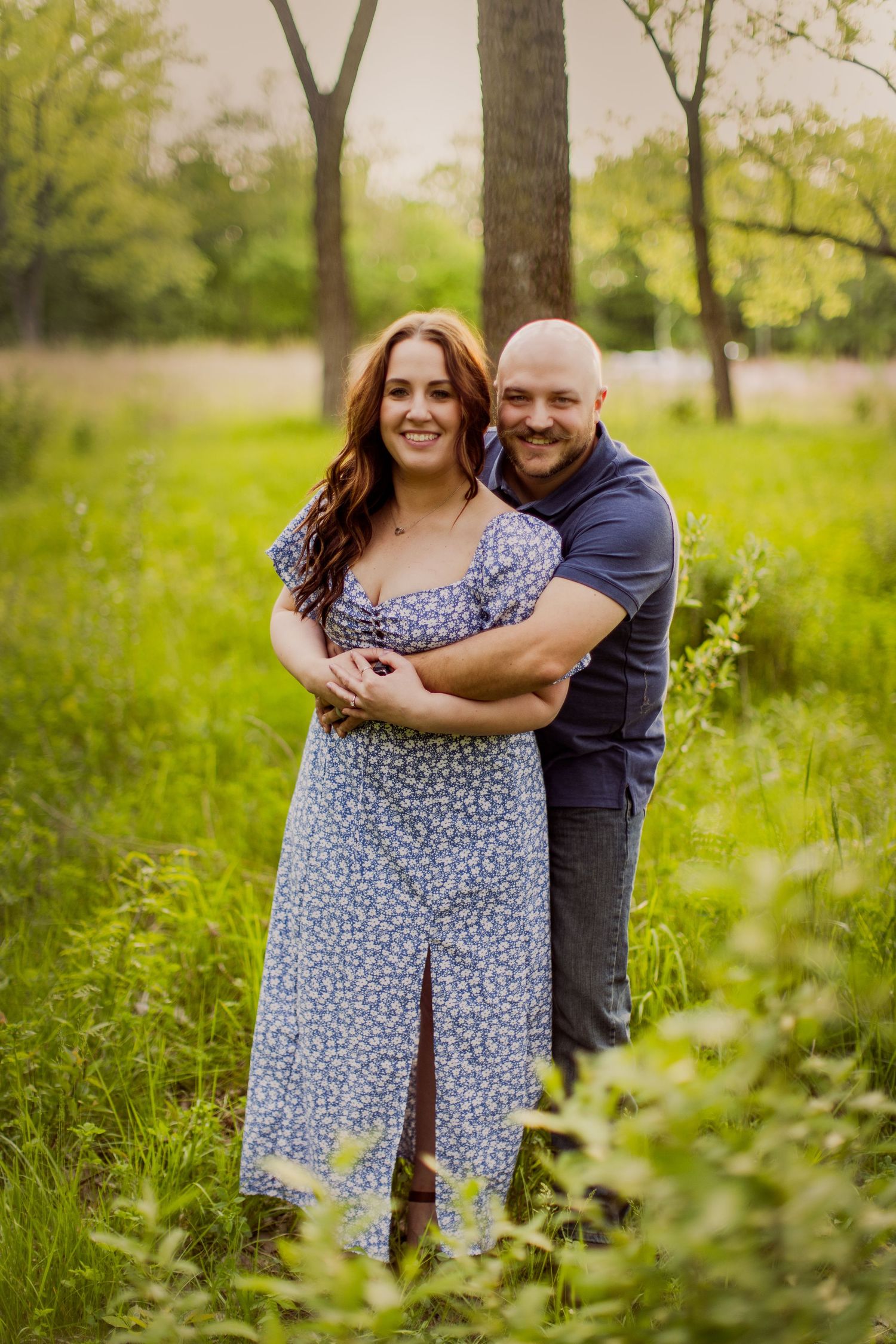 Joyful couple poses together in lush green spring garden setting.