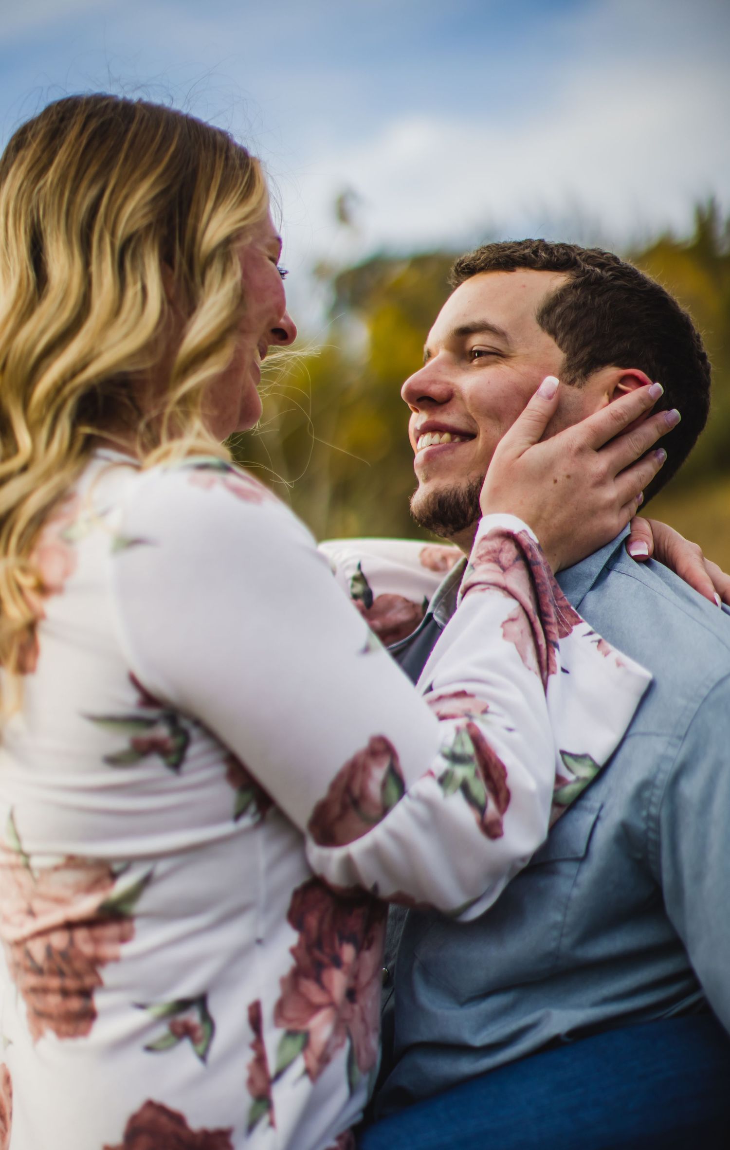 Close-up candid photo of a couple sharing an intimate moment with autumn colors in background.