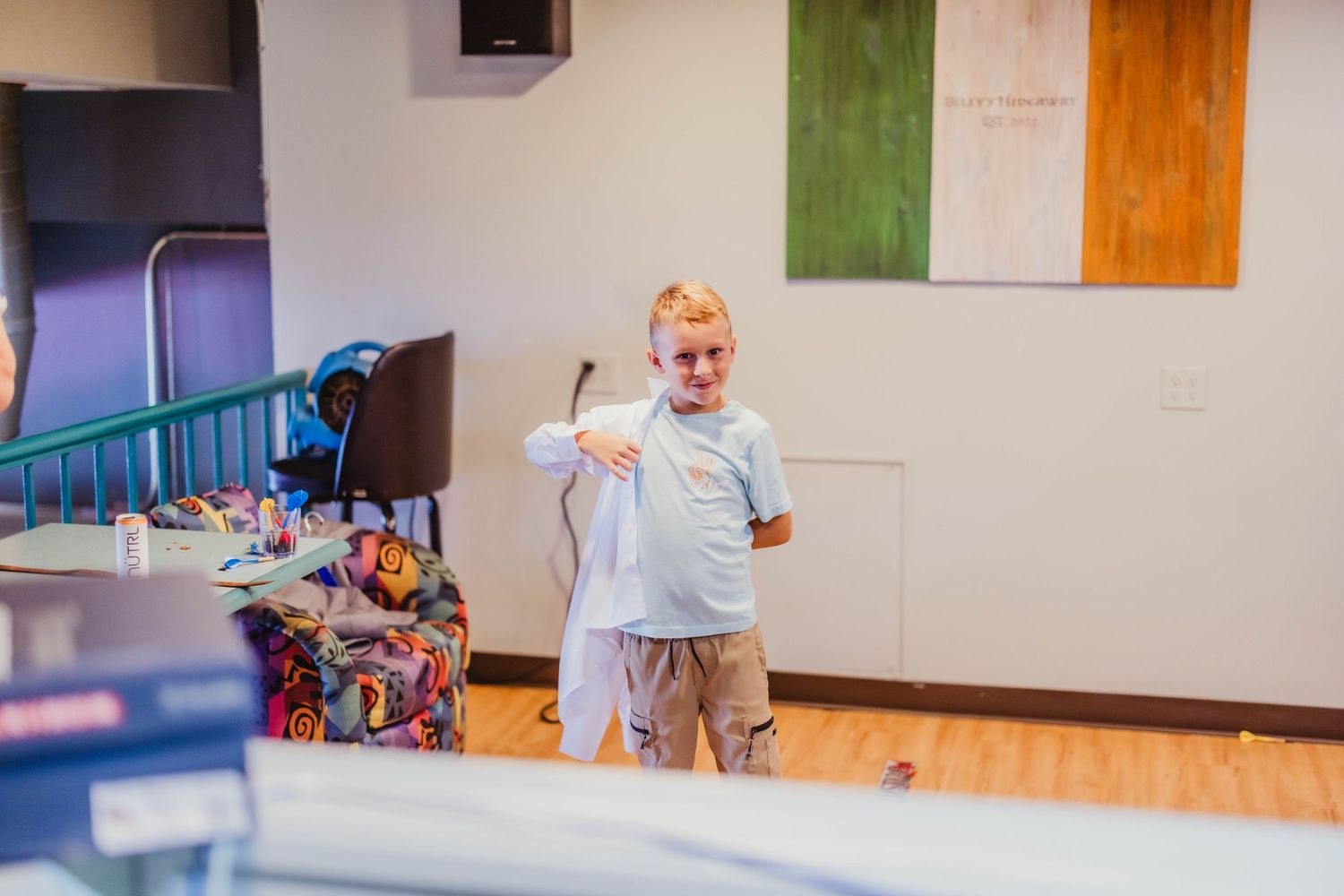 Young person playing table tennis in a gymnasium with an Irish flag on the wall.