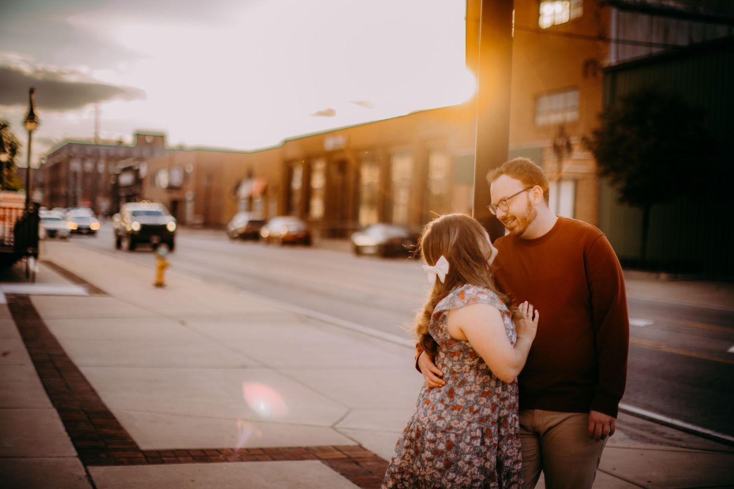Warm sunset light illuminates an urban street as a couple shares a romantic moment.