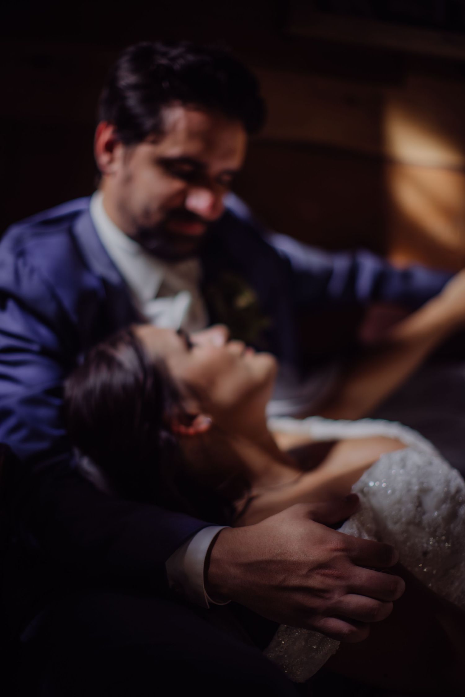 Wedding couple sharing a romantic moment in dramatic low lighting.