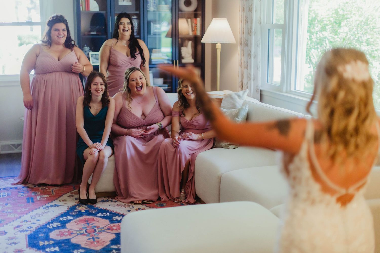 Wedding party members share a candid moment while lounging in a light-filled room.