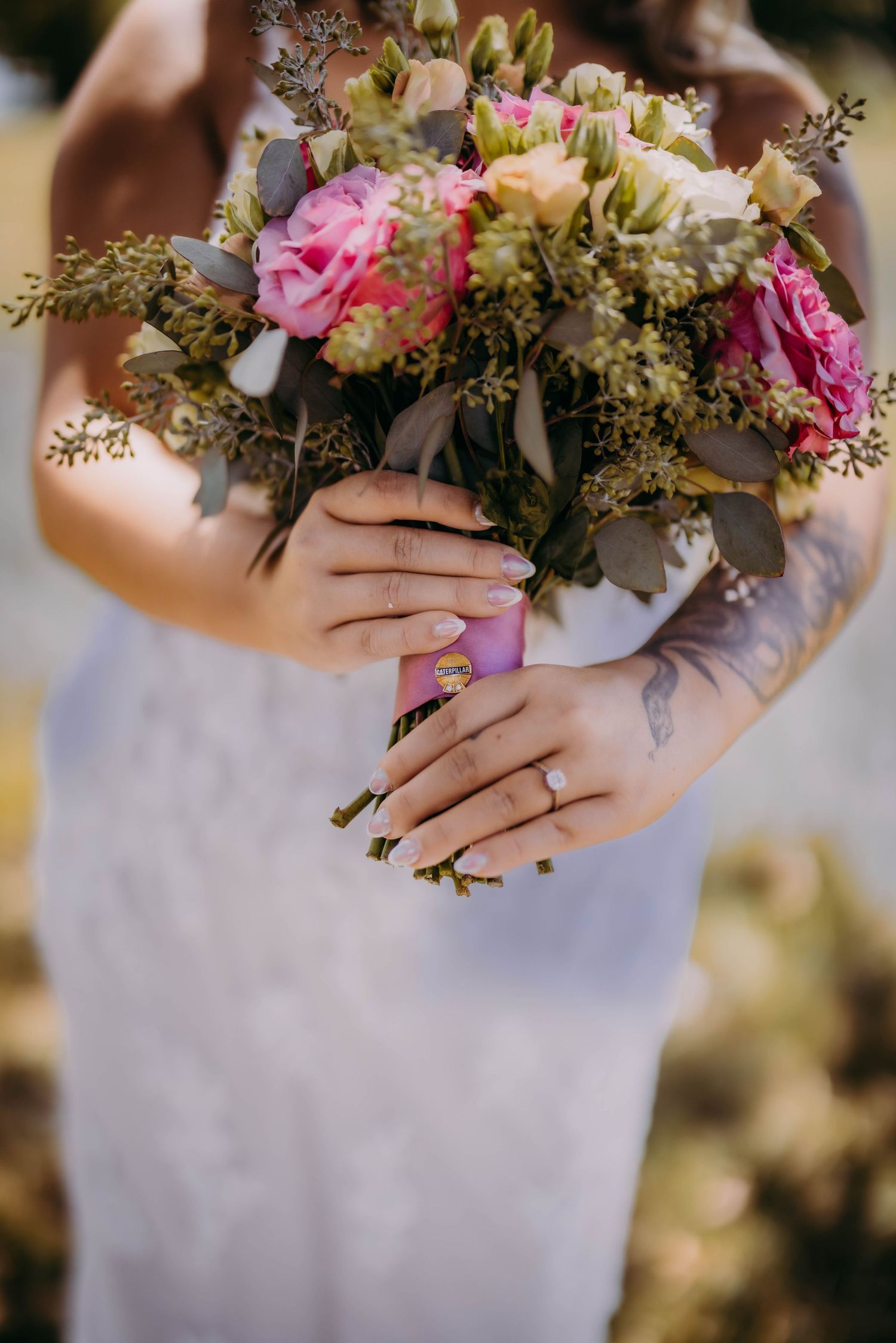 Close-up of pink and white wedding bouquet with greenery and roses.