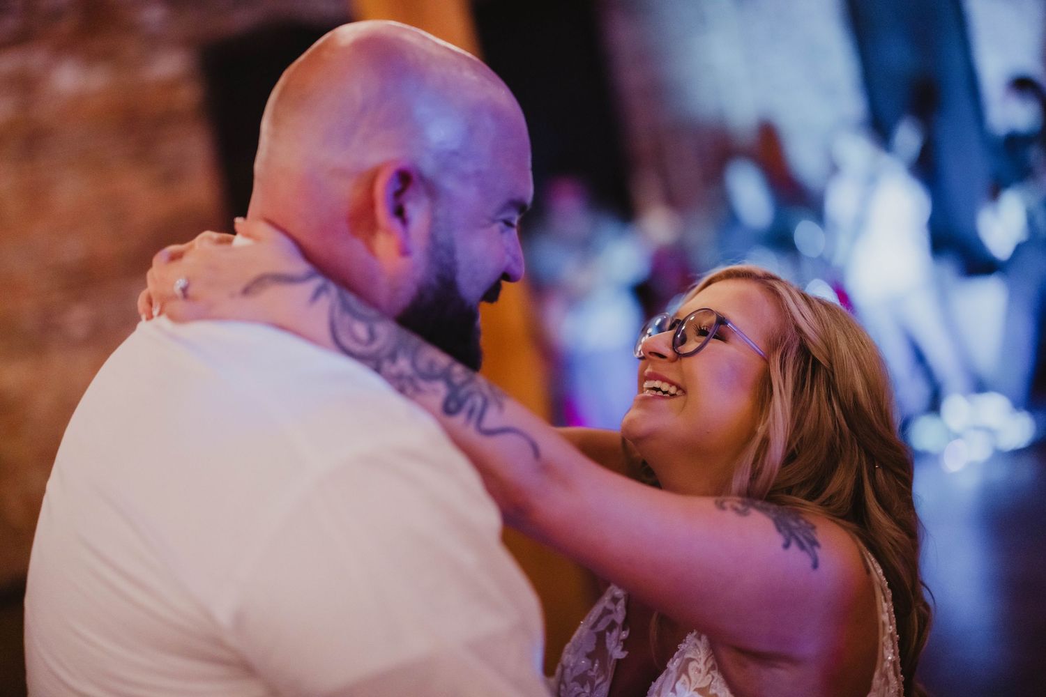 A couple shares an intimate dance at their wedding reception with blue lighting and romantic atmosphere.