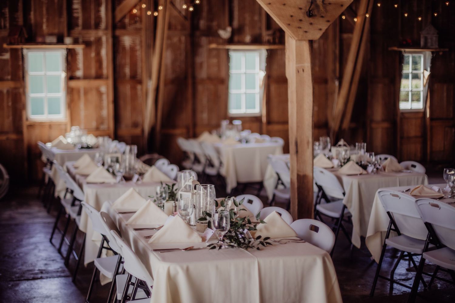 Wedding venue interior with exposed wooden beams and elegant table settings.