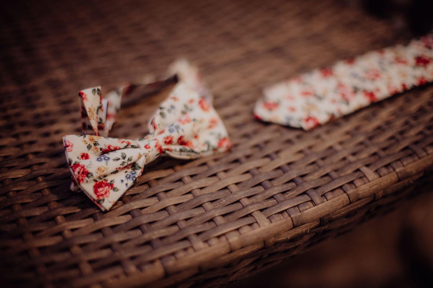 Floral print bow ties arranged on woven wicker surface.
