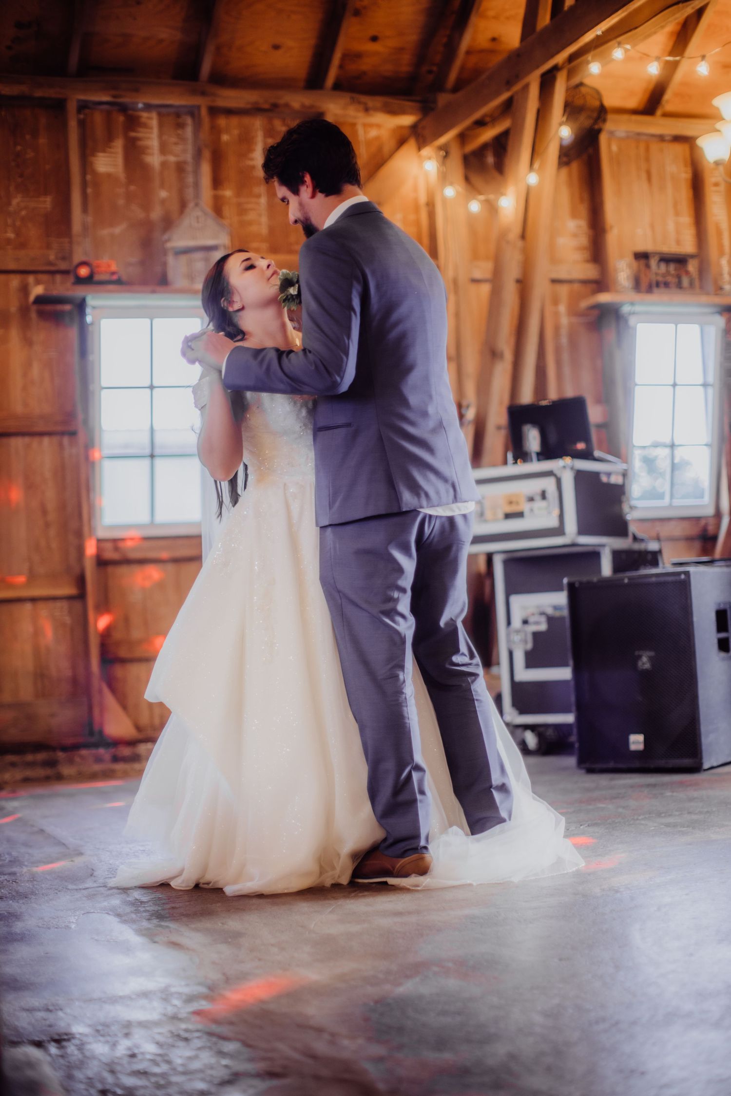 Couple dancing in an intimate barn venue with wooden beams and natural lighting.