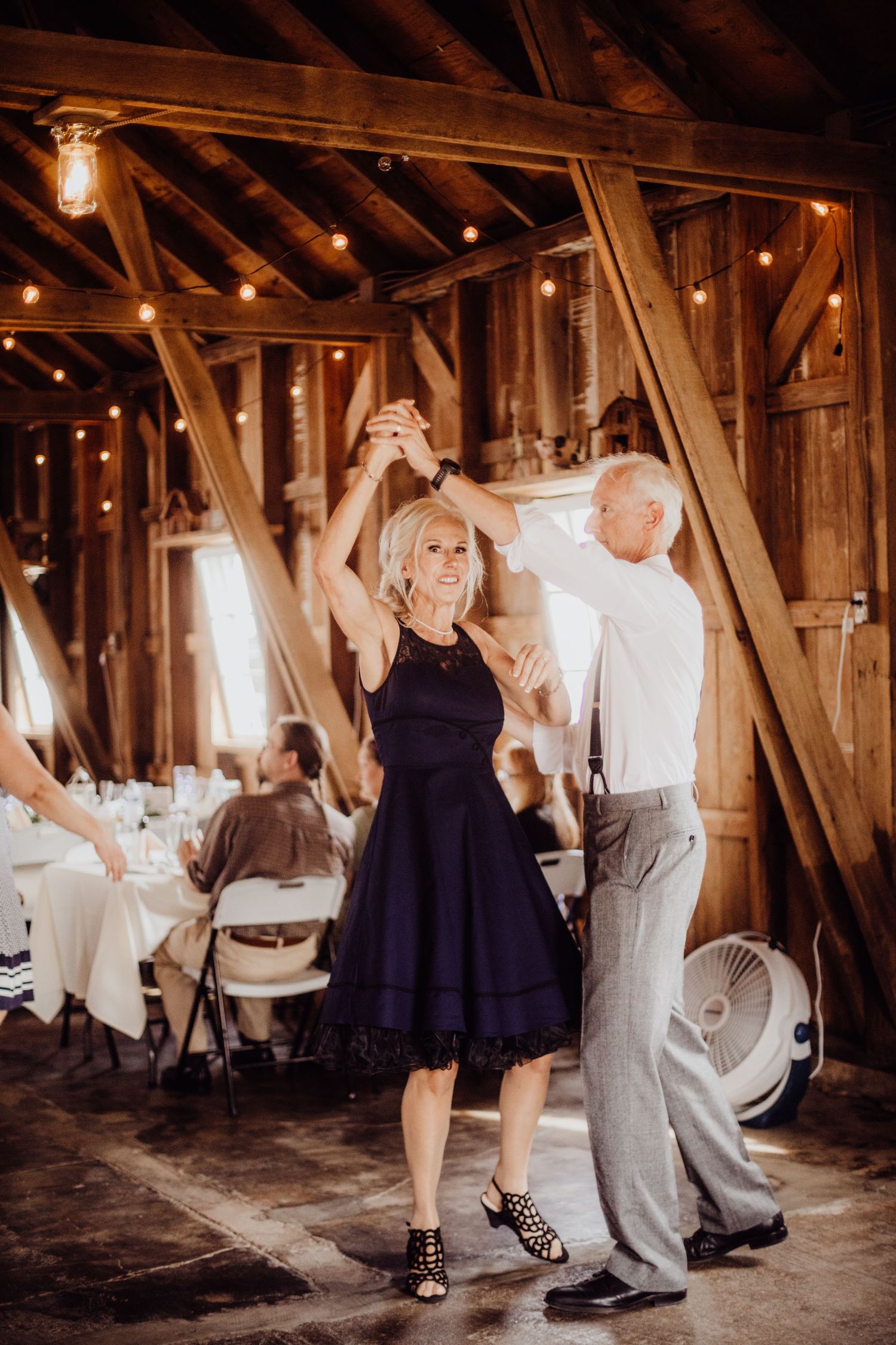 Dancing couples enjoy a romantic moment in an intimate barn setting with ambient lighting.
