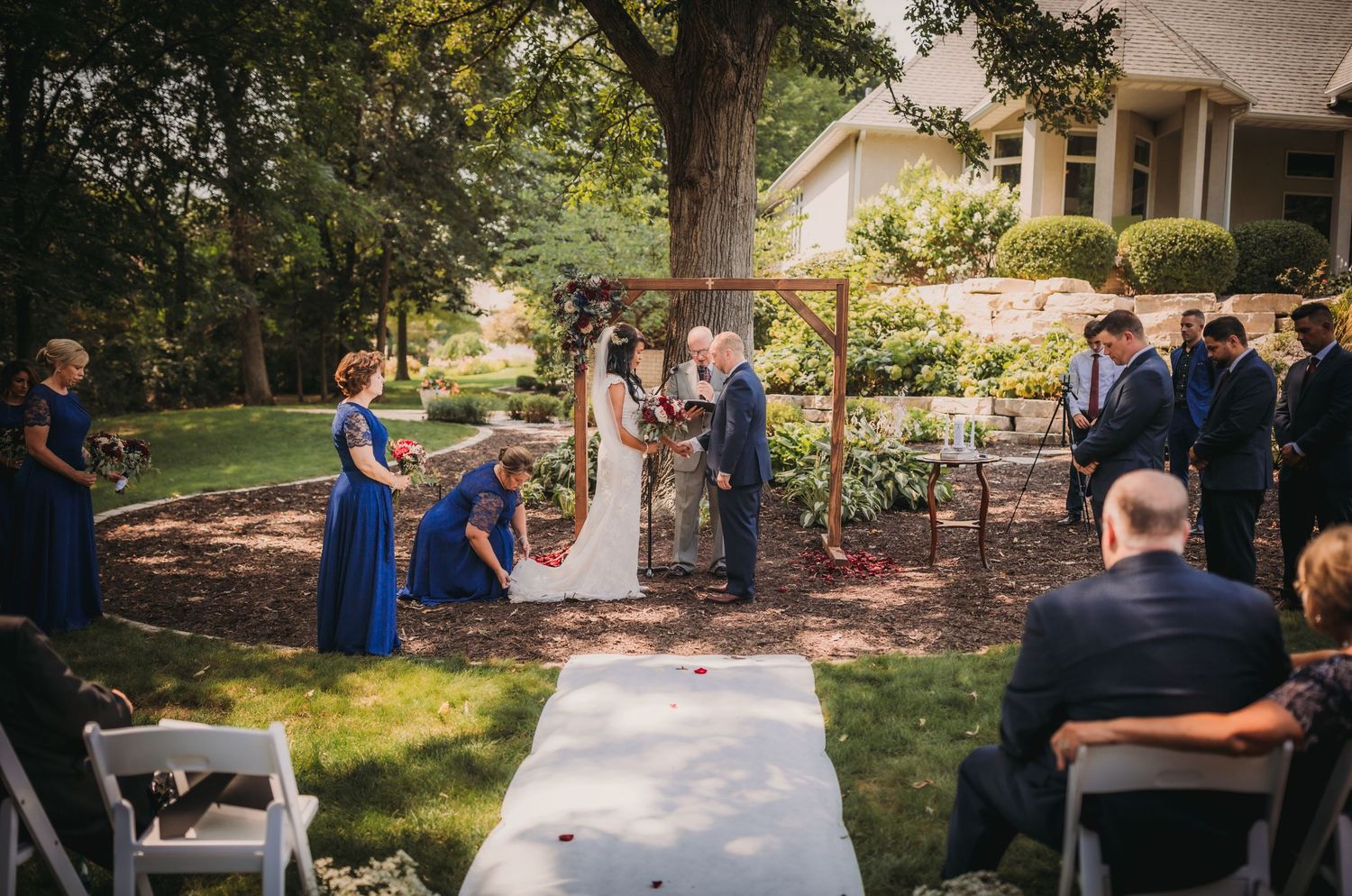 Scenic garden wedding setup with white aisle and natural tree canopy.