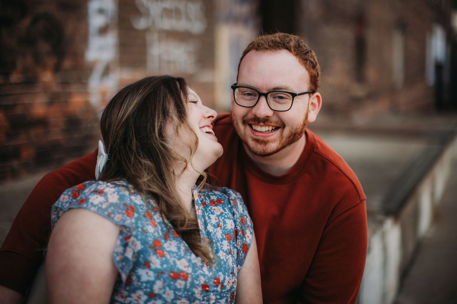 A joyful couple laughs together during their urban photo session.