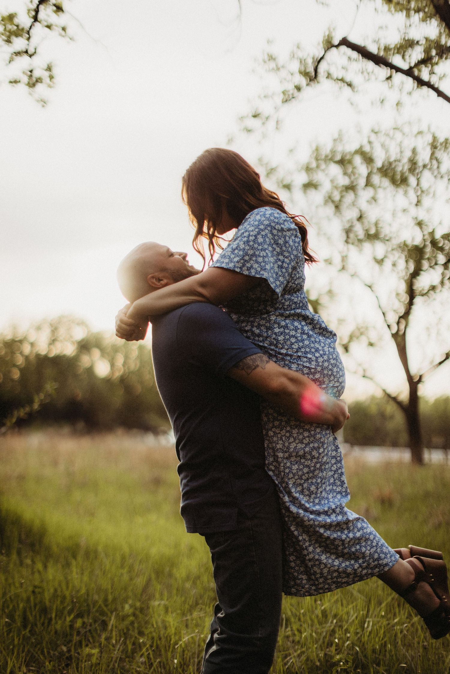 Romantic portrait of a couple embracing in a field during golden hour.