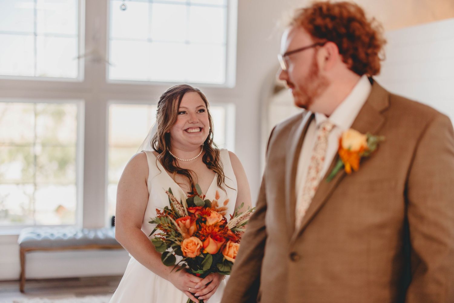 Candid moments of laughter and emotion during a wedding first look in a sun-filled venue.