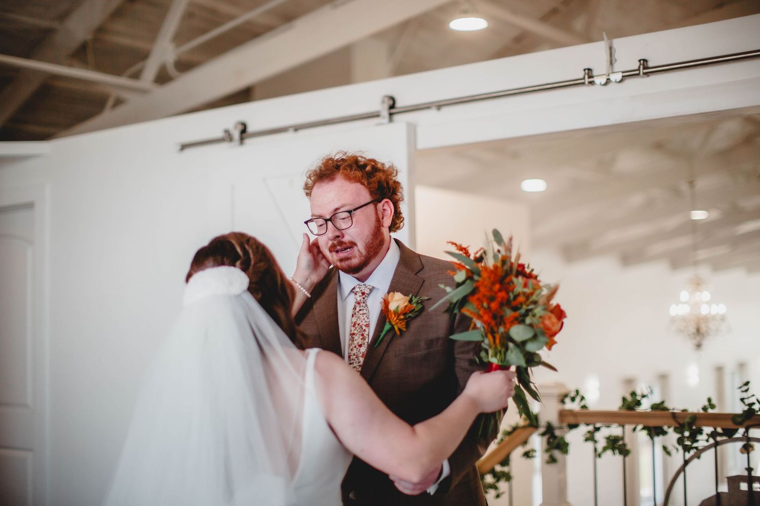 Tender moment captured during wedding first look with autumn-themed bouquet.