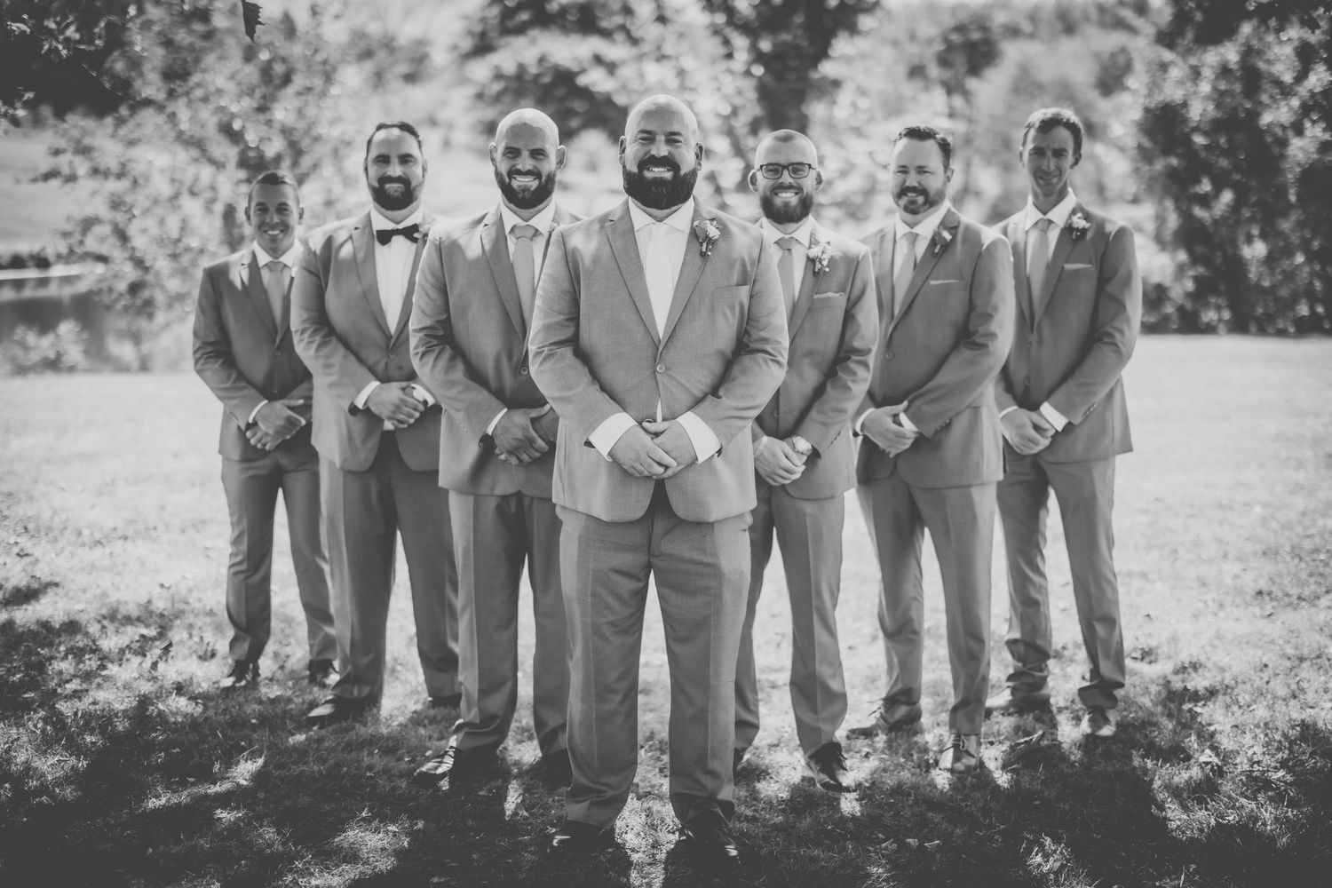 Monochrome photo of groomsmen in matching suits posing outdoors.