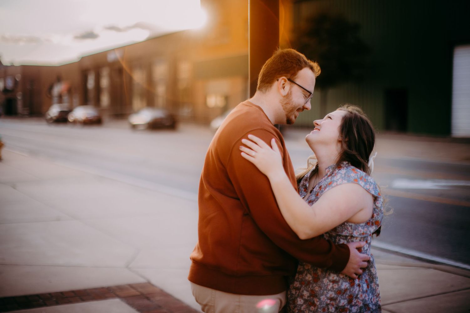 A romantic engagement portrait features a couple in casual attire during golden hour.