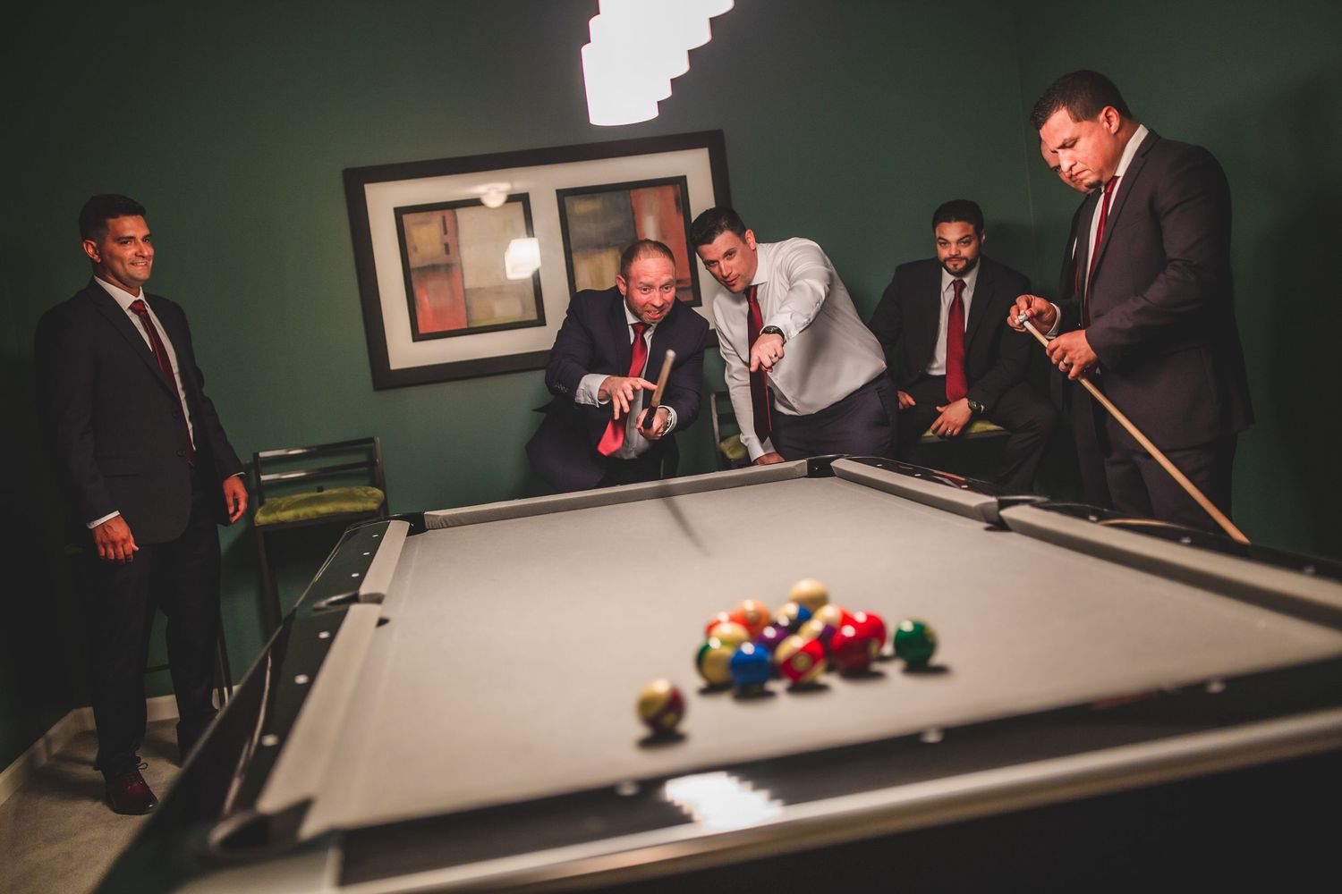 Friends enjoying a game of pool during a formal gathering.