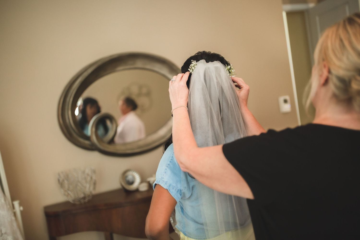 Behind the scenes view of wedding veil being carefully arranged during bridal preparation.