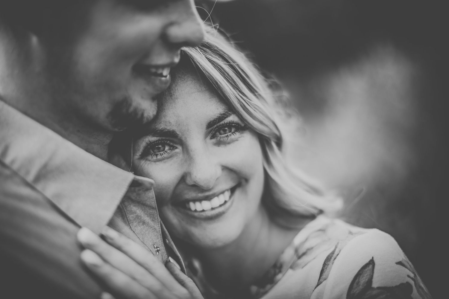 Black and white close-up photo capturing genuine laughter and love between a couple.