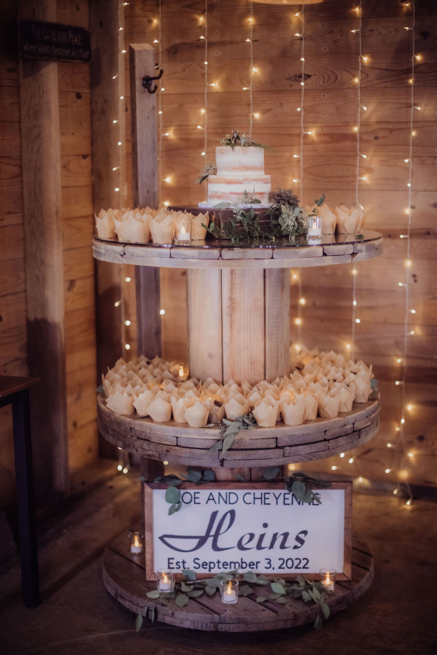 Three-tier wedding cake display with fairy lights and name sign for Joe and Cheyenne Heins.