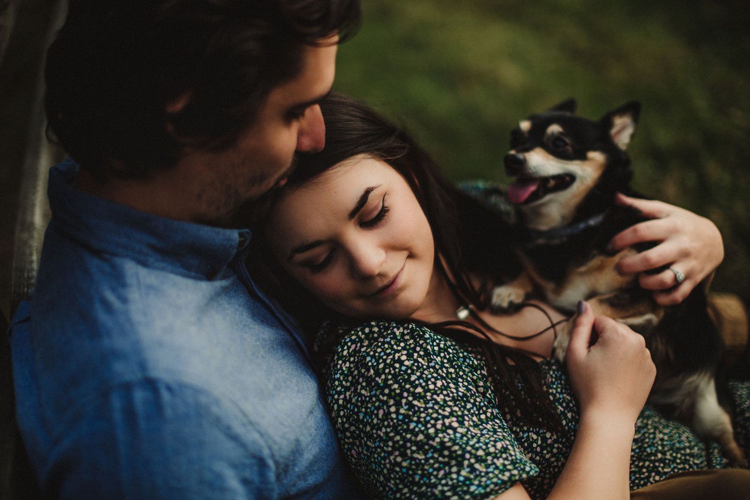 Romantic couple relaxes outdoors with their small dog in a tender embrace.