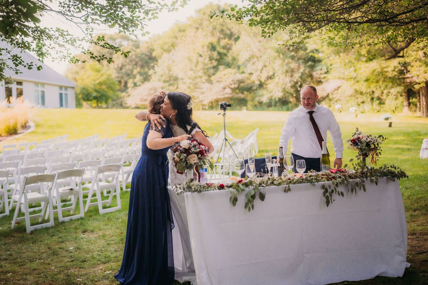 Woodland wedding reception featuring decorated white tables and navy blue color scheme.